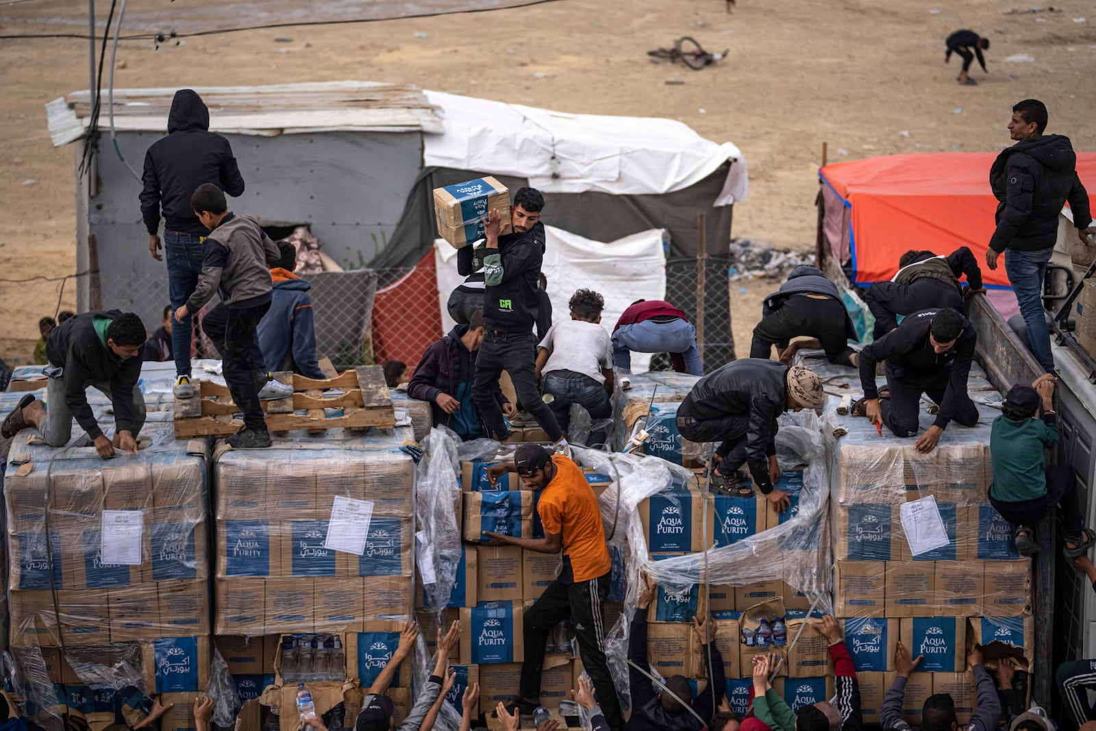 FILE - Palestinians grab humanitarian aid from a truck as it crossed into the Gaza Strip in Rafah, Sunday, Dec. 17, 2023. (AP Photo/Fatima Shbair, File)