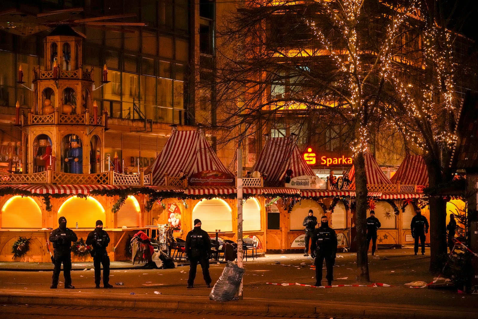 Security guards stand in front of a cordoned-off Christmas Market after a car crashed into a crowd of people, in Magdeburg, Germany, Saturday early morning, Dec. 21, 2024. (AP Photo/Ebrahim Noroozi)