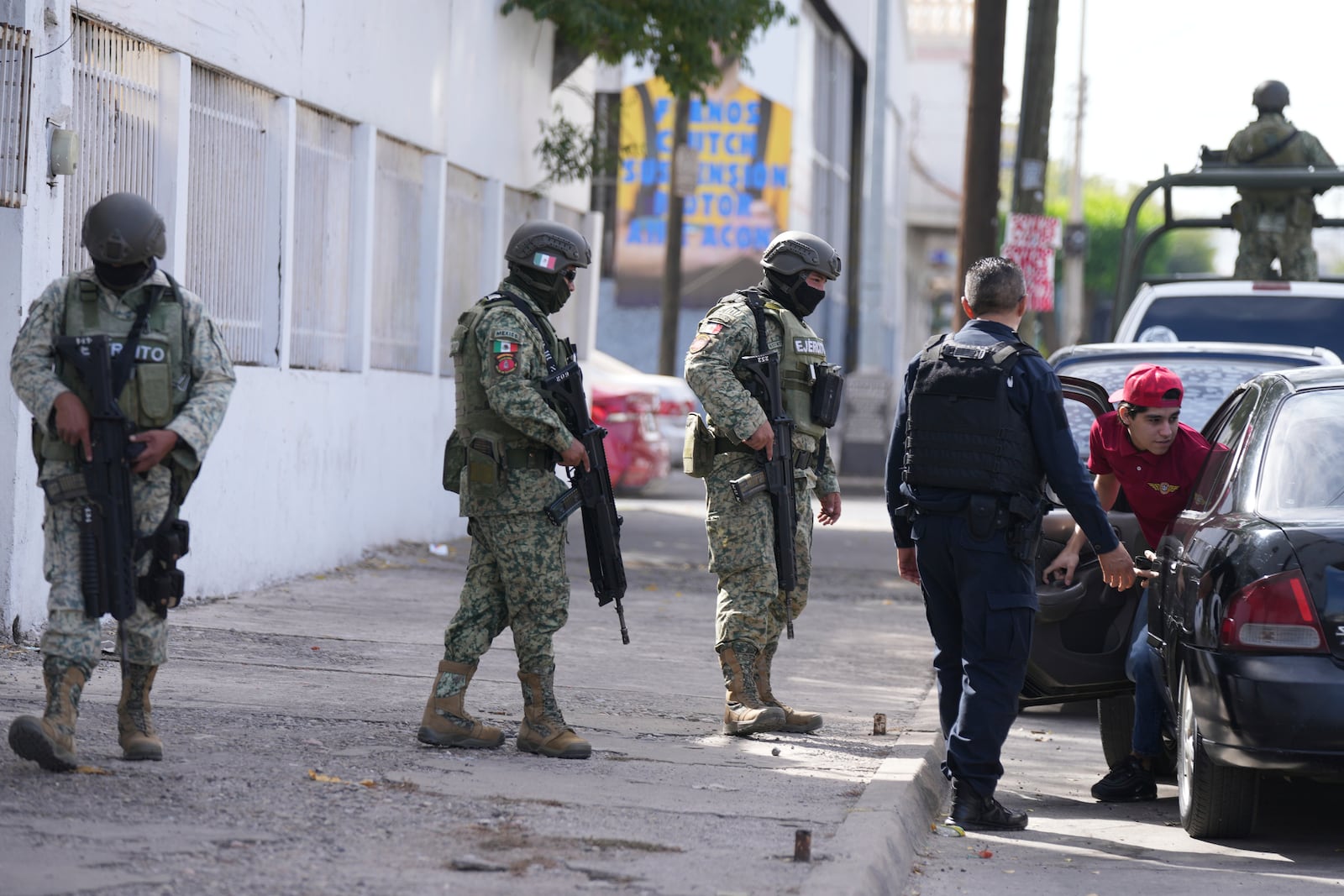 Police officers and soldiers inspect drivers at a checkpoint in Culiacan, Sinaloa state, Mexico, Wednesday, Feb. 26, 2025. (AP Photo/Fernando Llano)