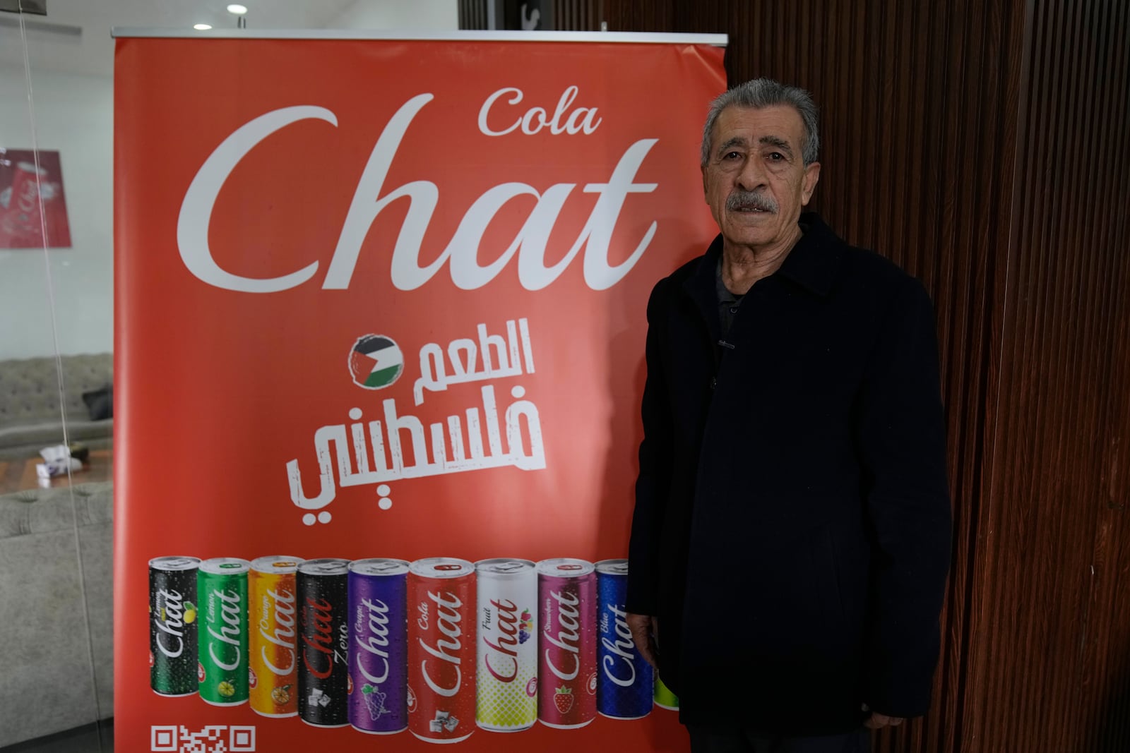 Fahed Arar, general manager of the Chat Cola Company poses next to an advertisement billboard with the companies brands and reads "the Palestinian taste," in the Palestinian company's bottling plant, in the West Bank city of Salfit, Feb. 13, 2025. (AP Photo/Nasser Nasser)