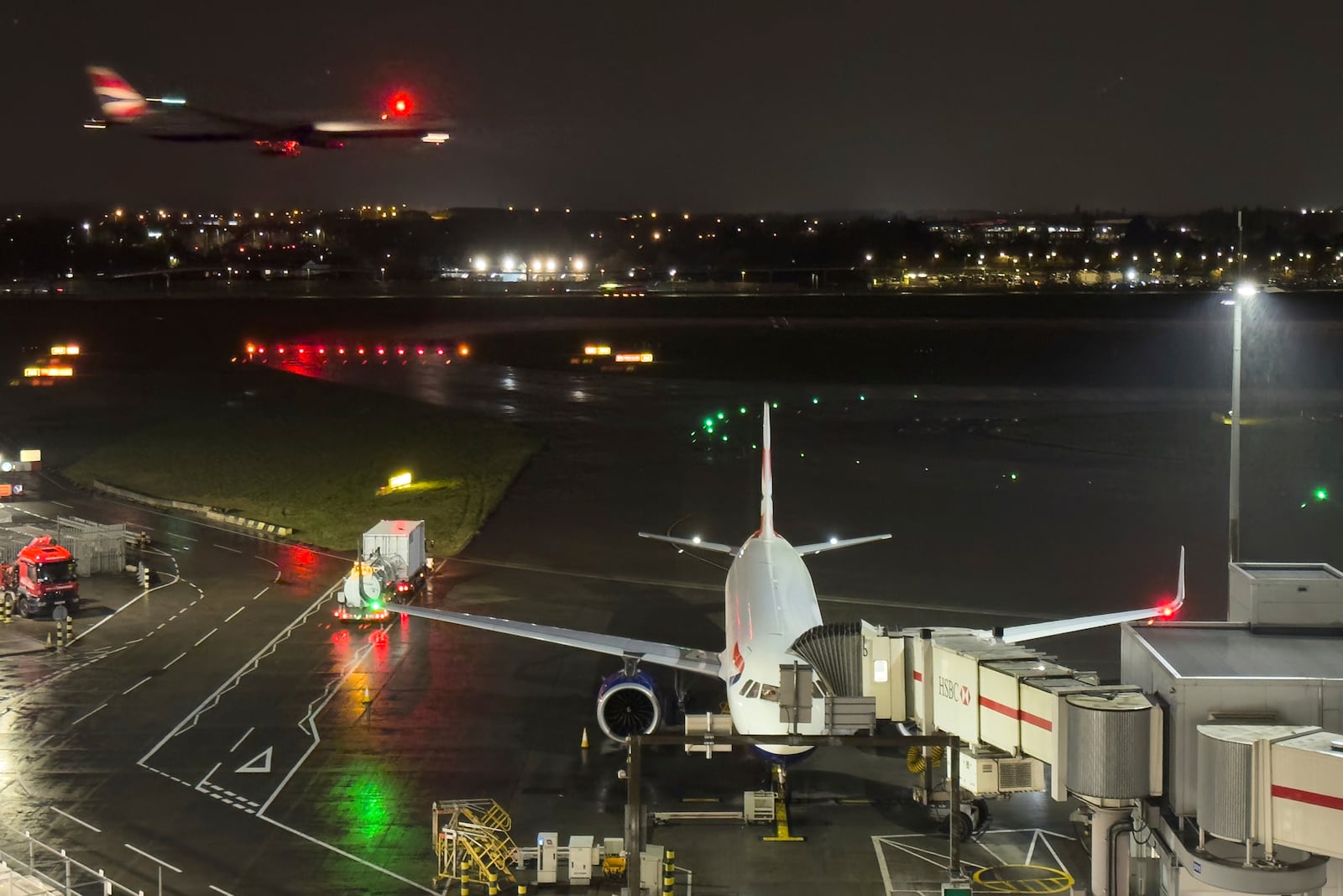 A plane is prepared whilst another airplane approaches landing at Heathrow Airport after a fire at an electrical substation shuttered Europe's busiest air travel hub in London, Friday, March 21, 2025.(AP Photo/Alberto Pezzali)