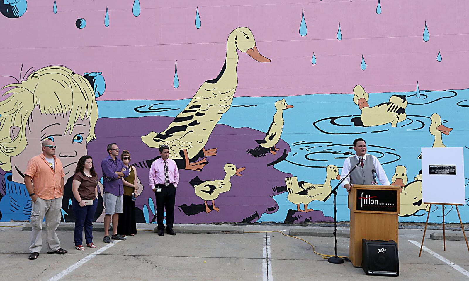 Ian MacKenzie-Thurley, executive director of the Fitton Center for Creative Arts, speaks during the dedication of the Robert McCloskey mural at 20 High St. in Hamilton in 2016. The mural depicts some of McCloskey works, including “Blueberries for Sal” and “Make Way for Ducklings.” 