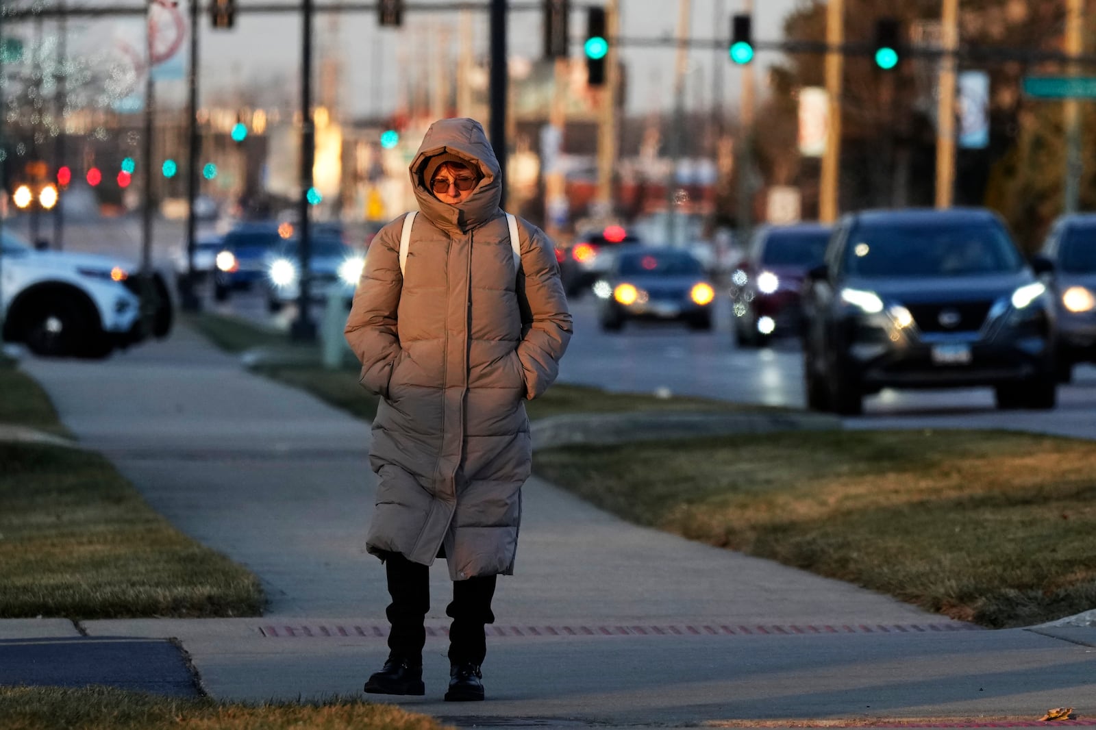 A pedestrian bundles up as she walks on the sidewalk during cold weather in Wheeling, Ill., Thursday, Dec. 12, 2024. (AP Photo/Nam Y. Huh)