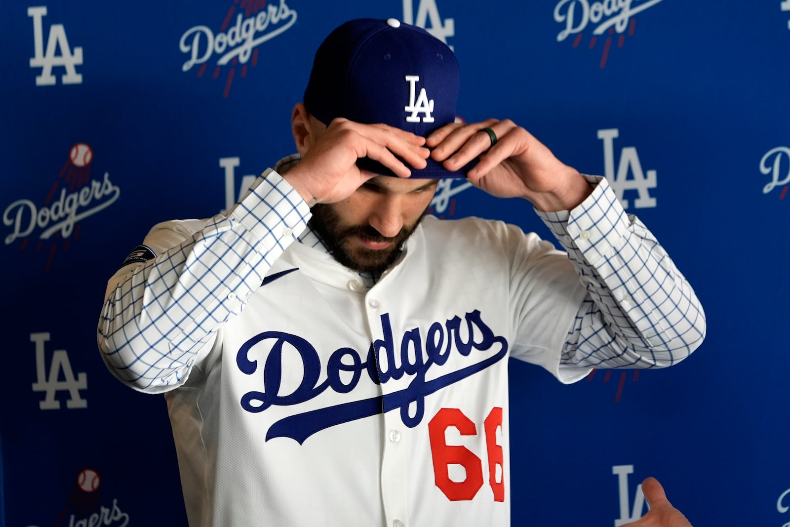 Left-handed new reliever Tanner Scott dons his new cap and jersey during an introduction baseball news conference at Dodger Stadium in Los Angeles, Thursday, Jan. 23, 2025. (AP Photo/Richard Vogel)