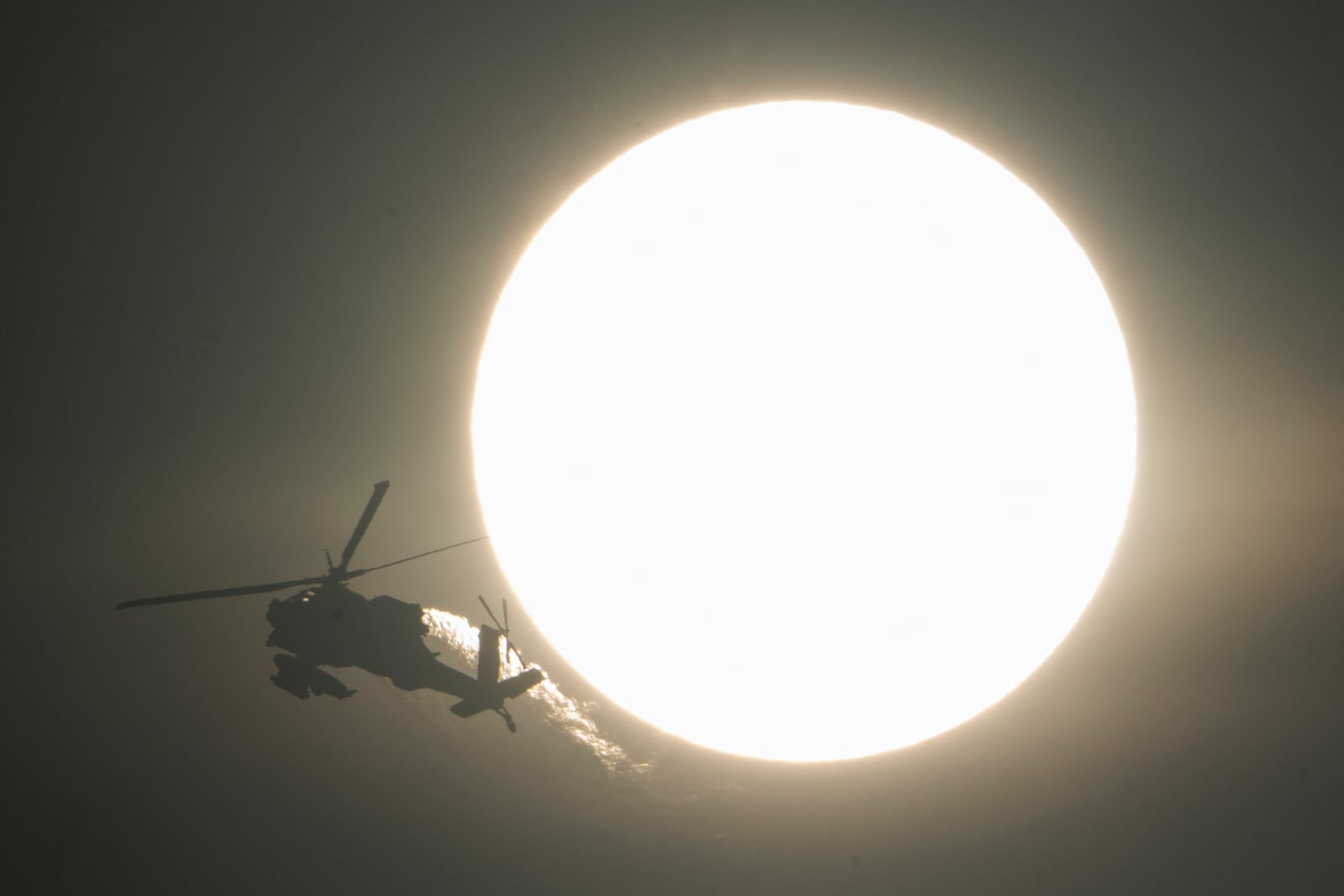 An Israeli Apache helicopter flies past the sun, near the Israeli-Lebanon border, as seen from northern Israel, Sunday, Oct. 13, 2024. (AP Photo/Leo Correa)