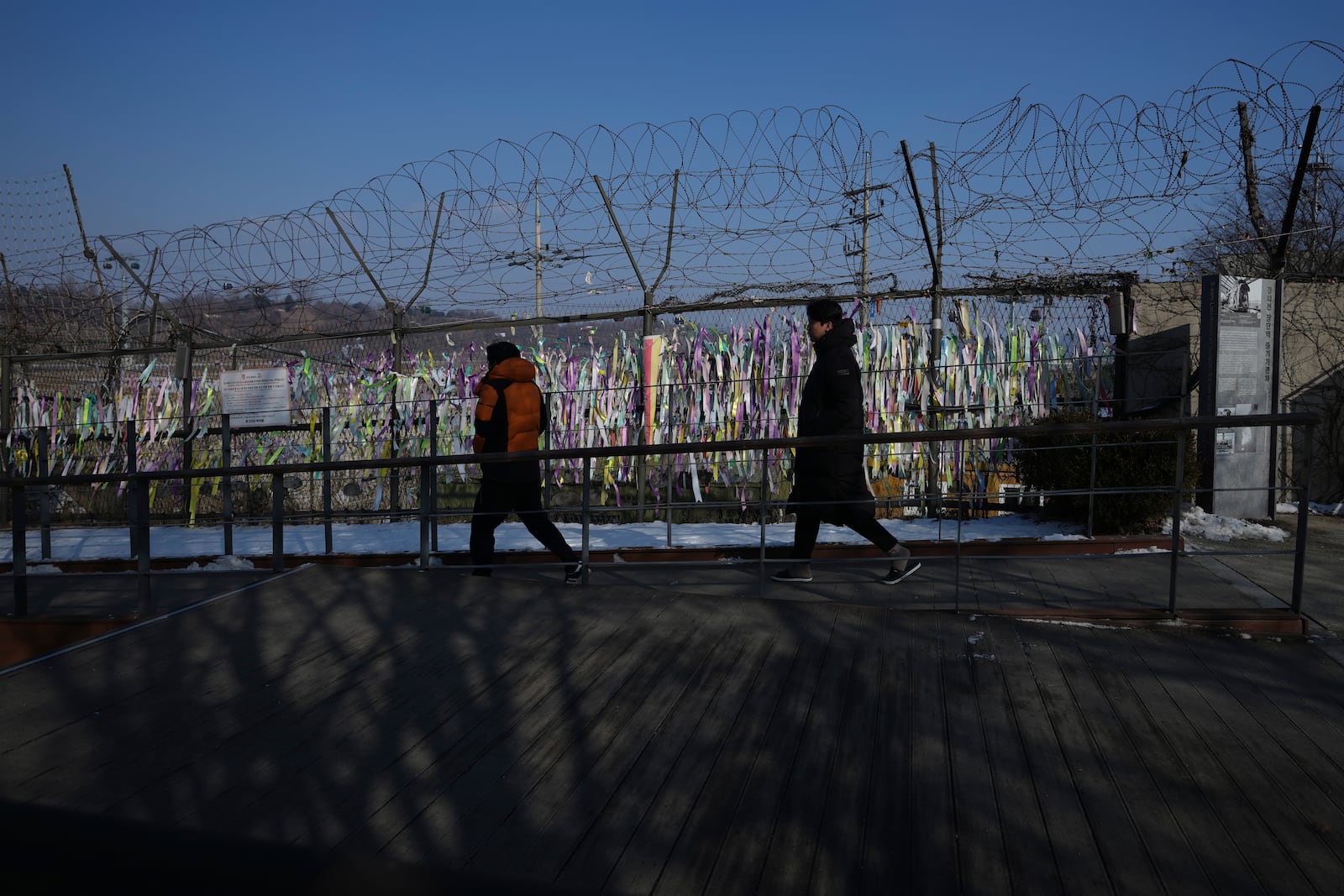 Visitors walk near a wire fence decorated with ribbons written with messages wishing for the reunification of the two Koreas at the Imjingak Pavilion in Paju, South Korea, Wednesday, Jan. 29, 2025. (AP Photo/Lee Jin-man)