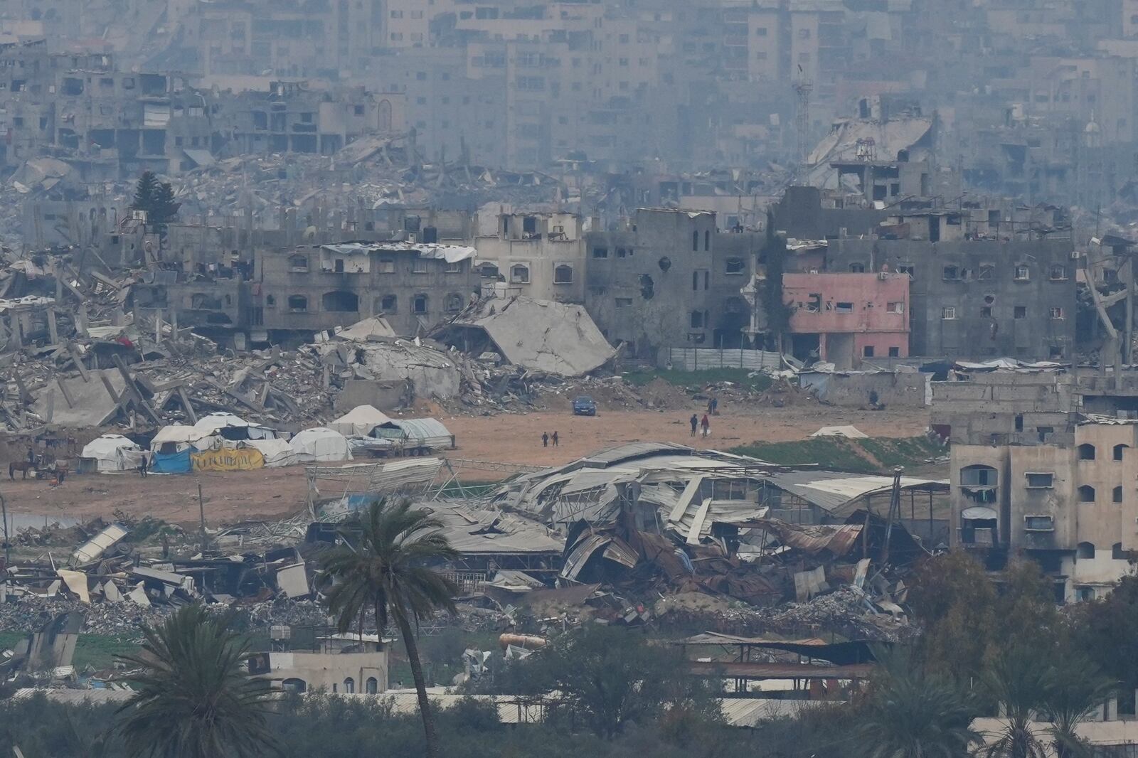 Palestinians are seen near destroyed buildings by Israeli bombardments inside the northern Gaza Strip as seen from southern Israel, Sunday, Feb. 9, 2025. (Photo/Ohad Zwigenberg)