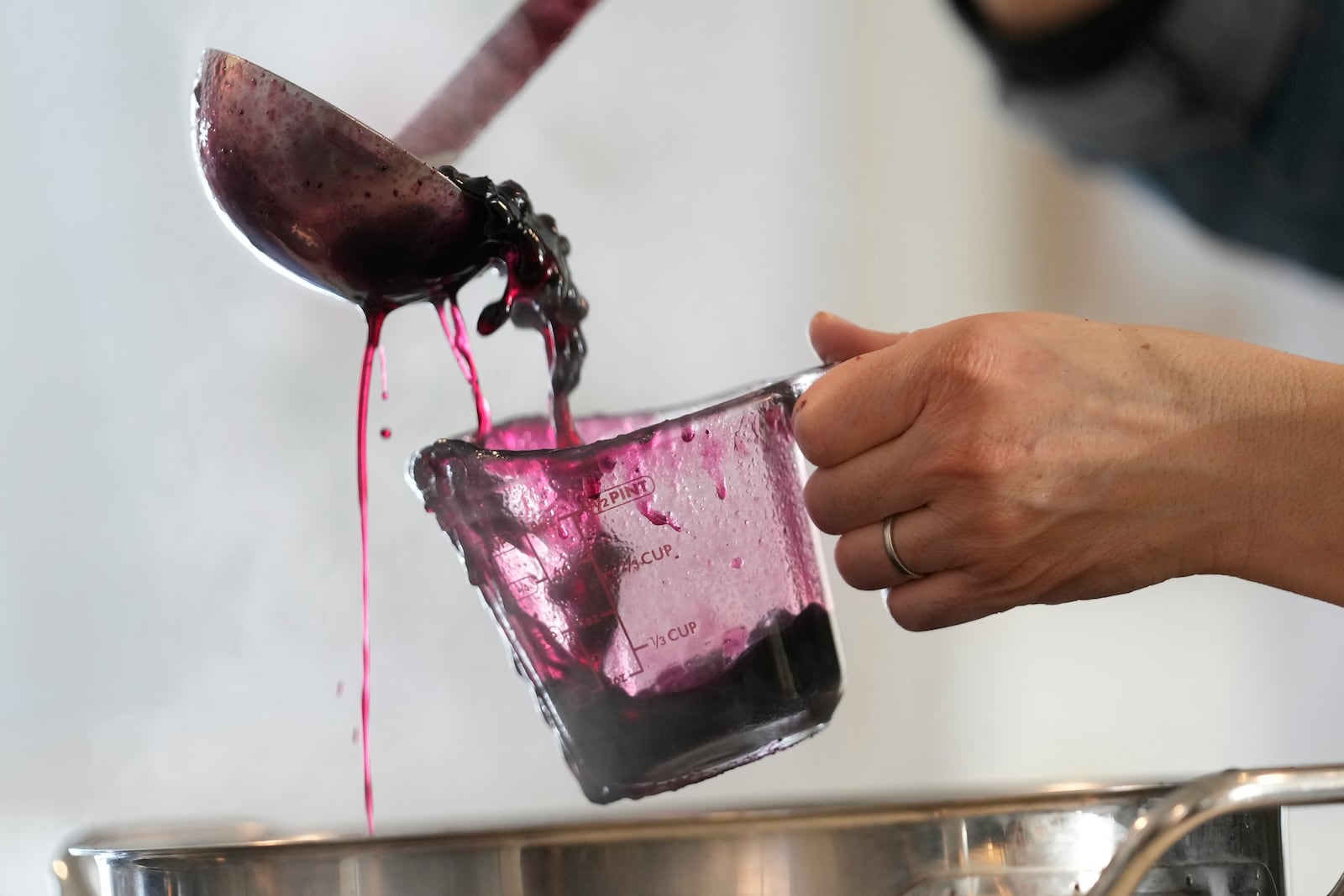 Jenny Lassen pours cooked wild blueberries into a measuring cup while canning the fruit, Monday, Feb. 10, 2025, in Cherryfield, Maine. (AP Photo/Robert F. Bukaty)