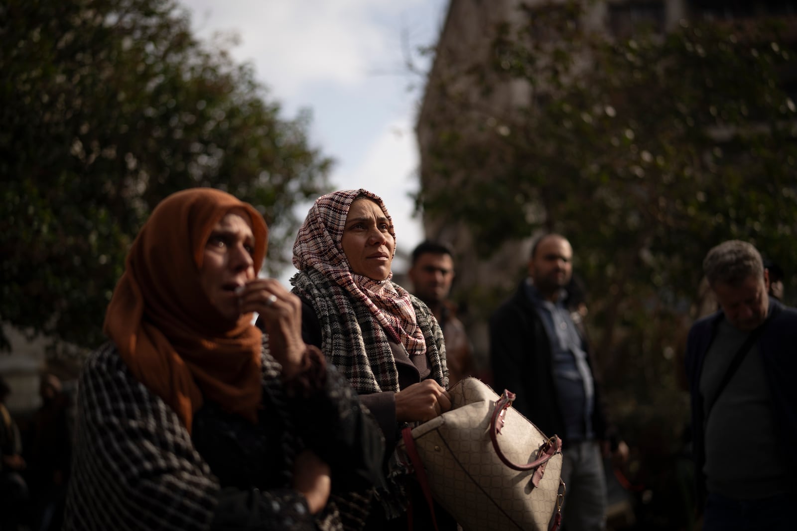 Hanaa, center, and her mother Khawla, left, who are searching for any information about her brother Hussam al-Khodr, look at photos of people reported to be missing by members of ousted Syrian President Bashar Assad's army, or a pro-government militia, in the Marjeh square in Damascus, Syria, Sunday, Dec. 22, 2024. According to Hanna, her brother was a soldier and went missing in 2014. (AP Photo/Leo Correa)