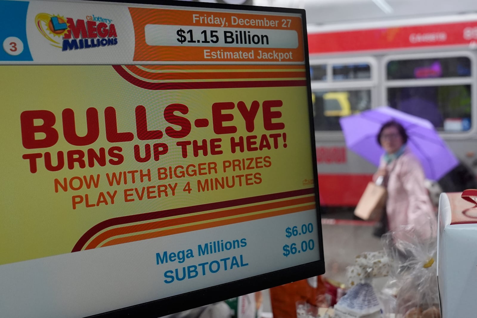 A pedestrian walks behind a sign advertising the estimated $1.15 billion Mega Millions jackpot at Rossi's Deli in San Francisco, Thursday, Dec. 26, 2024. (AP Photo/Jeff Chiu)