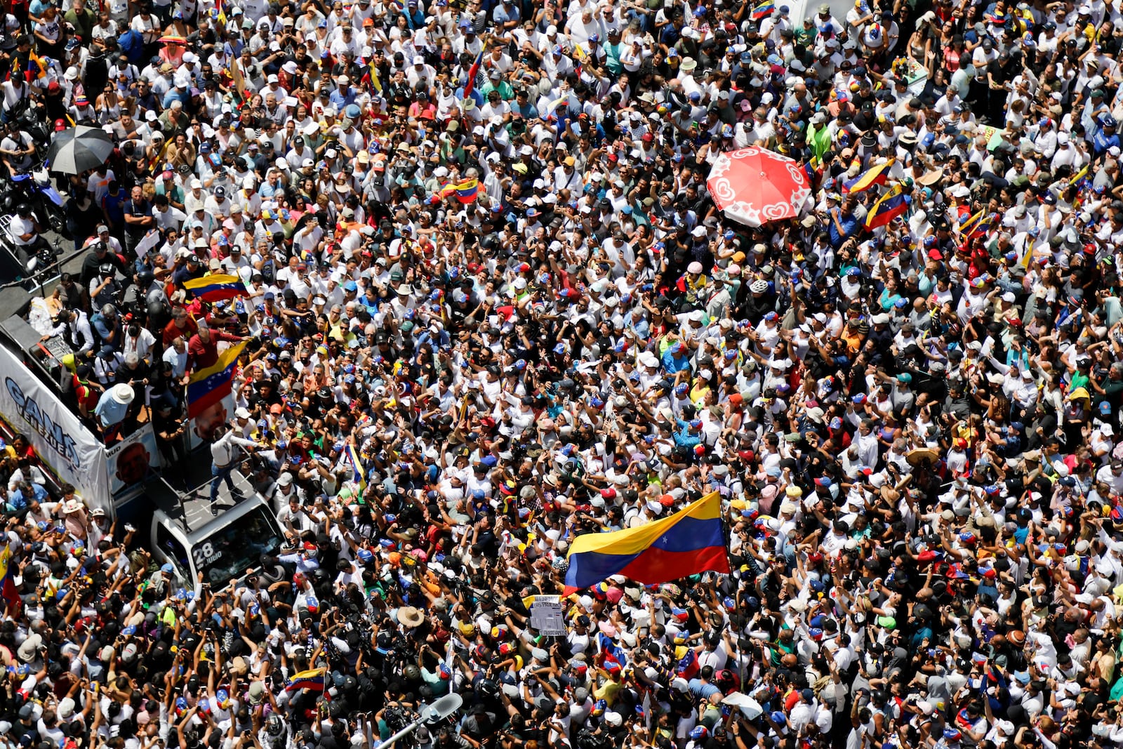 FILE - Opposition leader Maria Corina Machado, lower right, waves a Venezuelan national flag, during a rally to protest official results that declared President Nicolas Maduro the winner of the July presidential election, in Caracas, Venezuela, Aug. 17, 2024. (AP Photo/Cristian Hernandez, File)