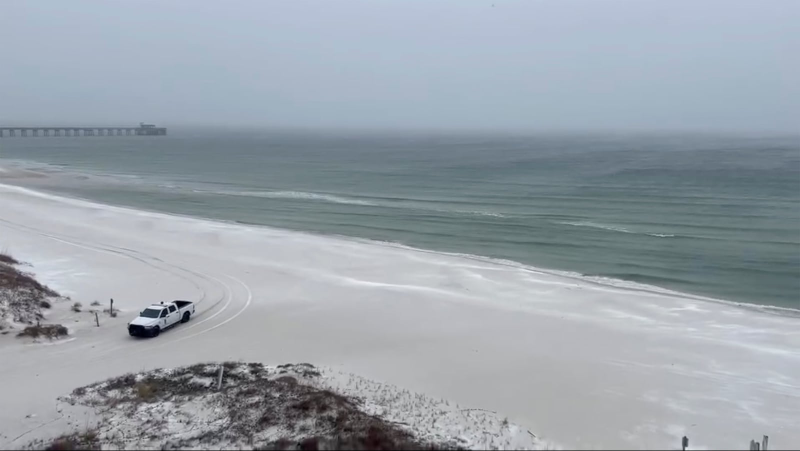 This photo provided by Kylee Thompson shows a truck driving on a snowy beach in Gulf Shores, Ala., on Tuesday, Jan. 21, 2025. (Kylee Thompson via AP)