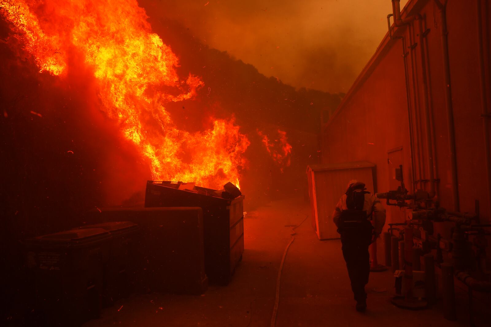 A firefighter protects a structure from the advancing Palisades Fire in the Pacific Palisades neighborhood of Los Angeles, Tuesday, Jan. 7, 2025. (AP Photo/Etienne Laurent)