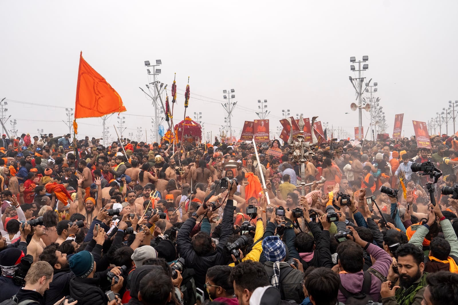 Media personnel jostle to photograph Hindu ascetics and holy men bathing at the confluence of the Ganges, the Yamuna and the mythical Saraswati rivers on the second day of the 45-day-long Maha Kumbh festival in Prayagraj, India, Tuesday, Jan. 14, 2025. (AP Photo/Ashwini Bhatia)