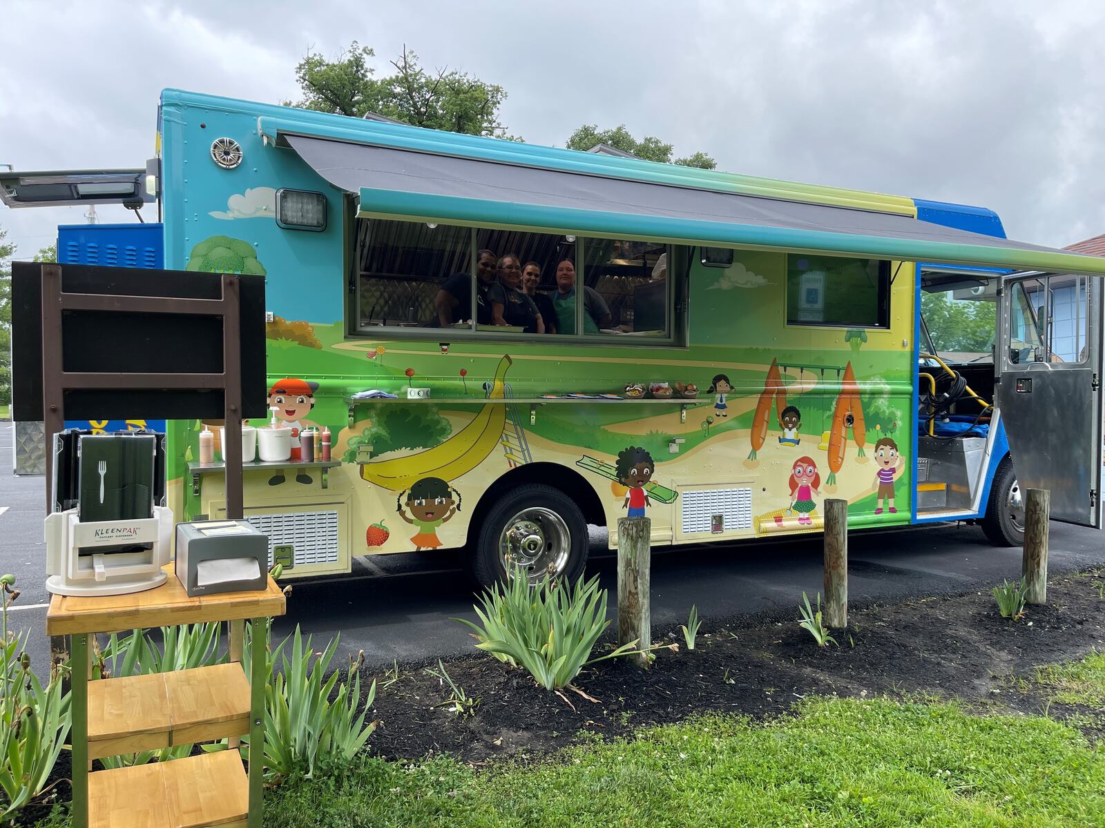 Staff who work in the cafeterias in the Hamilton City Schools are seen working in the Big Blue Food Truck at Crawford Woods. The truck moves around the city offering free lunches to students during the summer. Adults may buy a meal for $4. MANDY GAMBRELL/STAFF