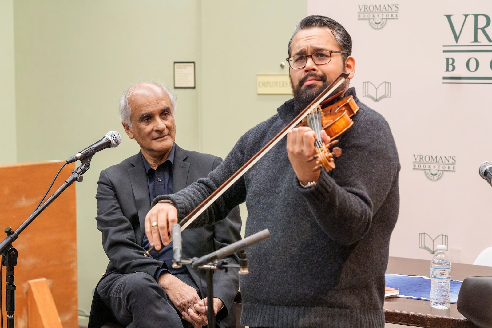 Violinist Vijay Gupta performs to introduce Pico Iyer, the bestselling author of "The Art of Stillness," left, presents his new book "Aflame: Learning from Silence" at Vroman's bookstore in Pasadena, Calif., on Tuesday, Jan. 28, 2025, in the wake of the devastating Eaton Fire that recently swept through parts of Pasadena and Altadena, forcing over 30,000 people to evacuate and burning thousands of structures. (AP Photo/Damian Dovarganes)