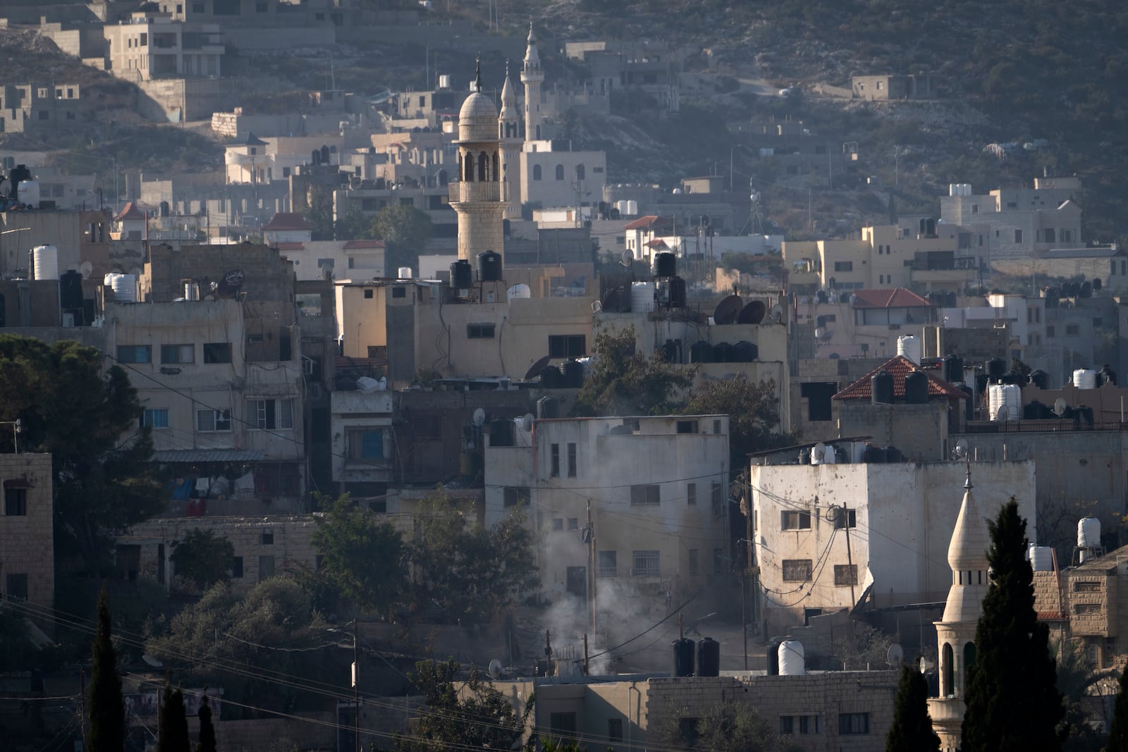 Smoke rises as Palestinian security forces mount a major raid against militants in the Jenin refugee camp in the Israeli-occupied West Bank, Monday, Dec. 23, 2024. (AP Photo/Majdi Mohammed)