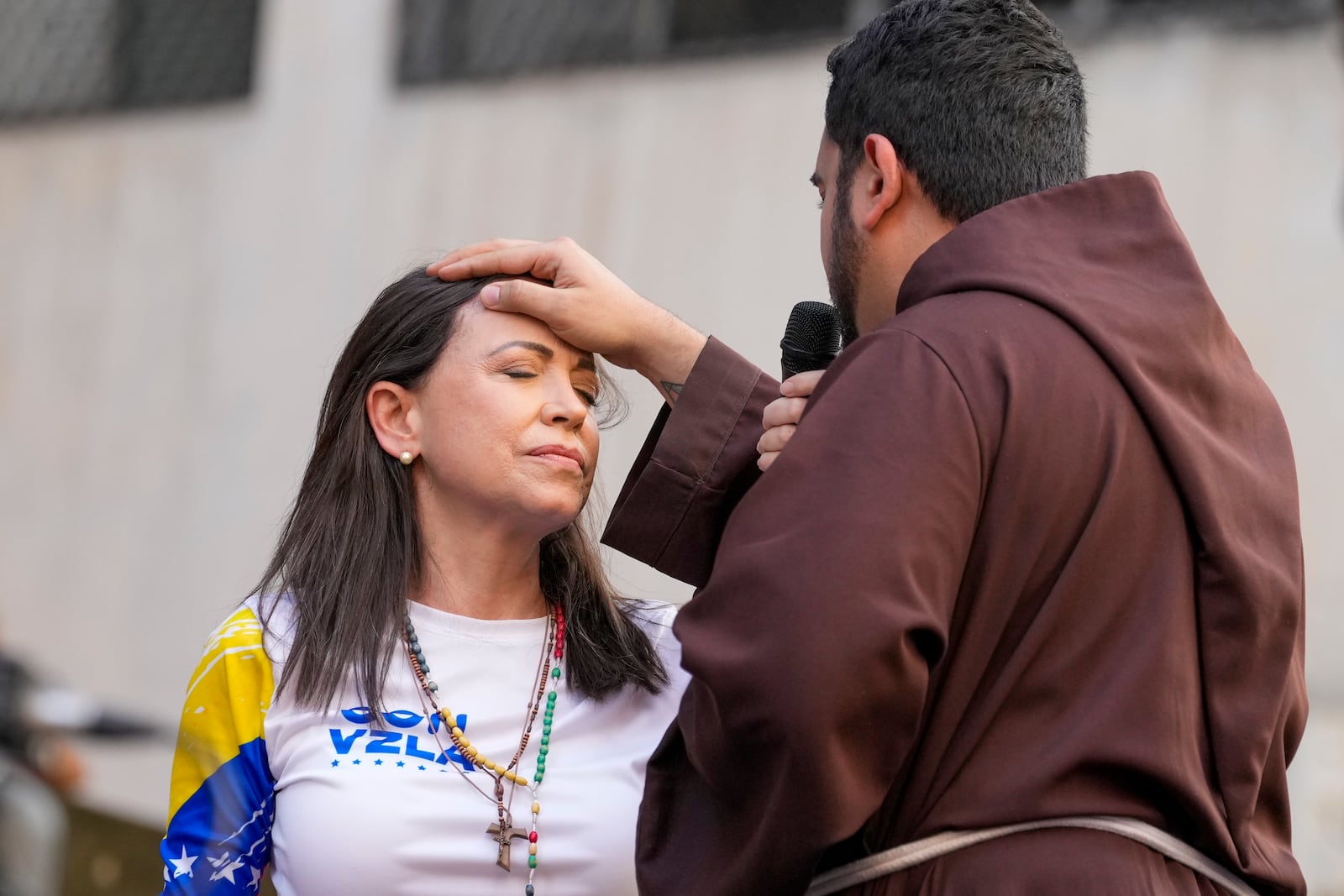 A priest blesses Venezuelan opposition leader Maria Corina Machado during a rally against President Nicolas Maduro the day before his inauguration for a third term, in Caracas, Venezuela, Thursday, Jan. 9, 2025. (AP Photo/Ariana Cubillos)