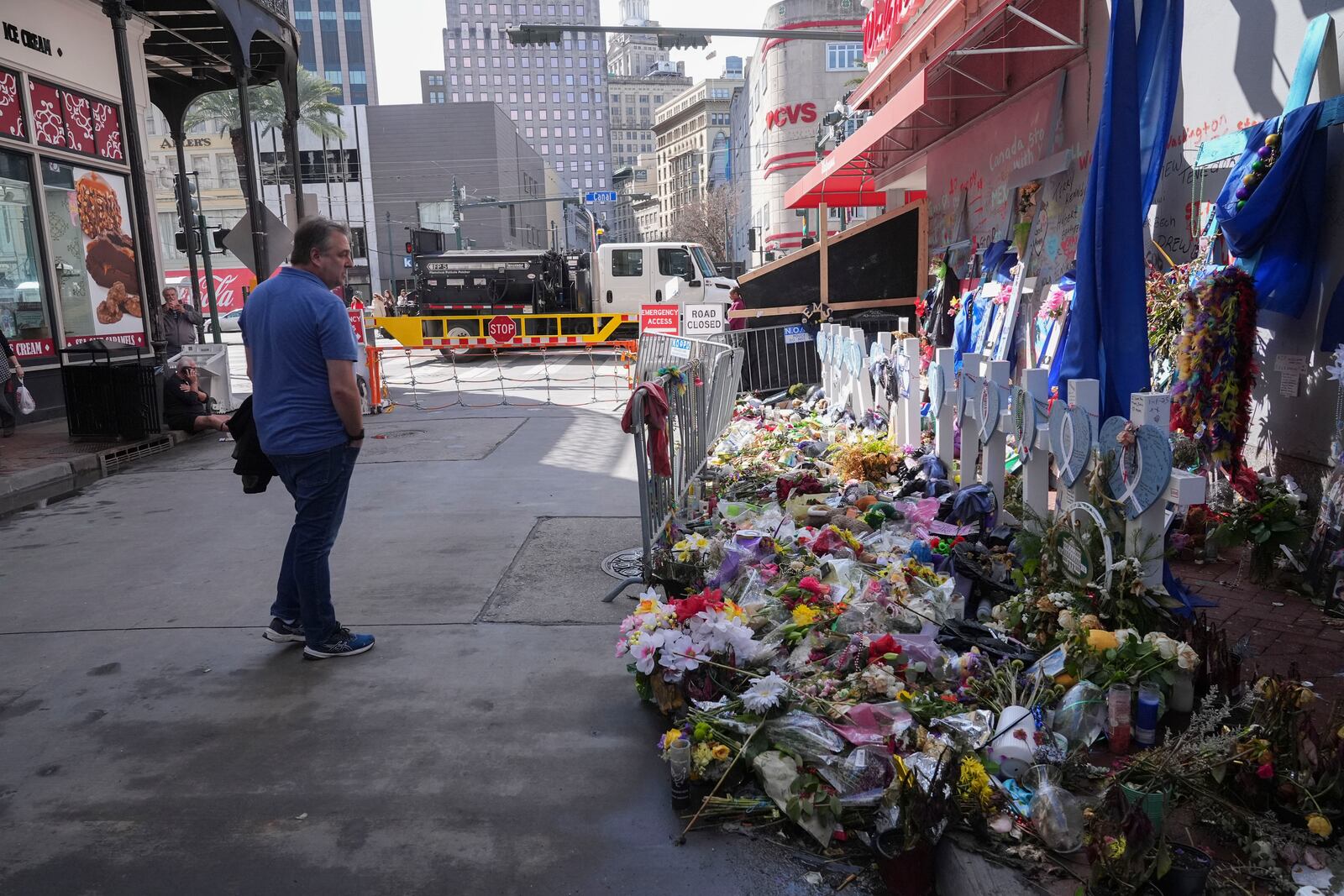 A man visits a memorial for victims of the Jan. 1 car attack where newly installed security barriers have since been put in place on Bourbon Street ahead of the Super Bowl in New Orleans, Friday, Jan. 31, 2025. (AP Photo/Gerald Herbert)