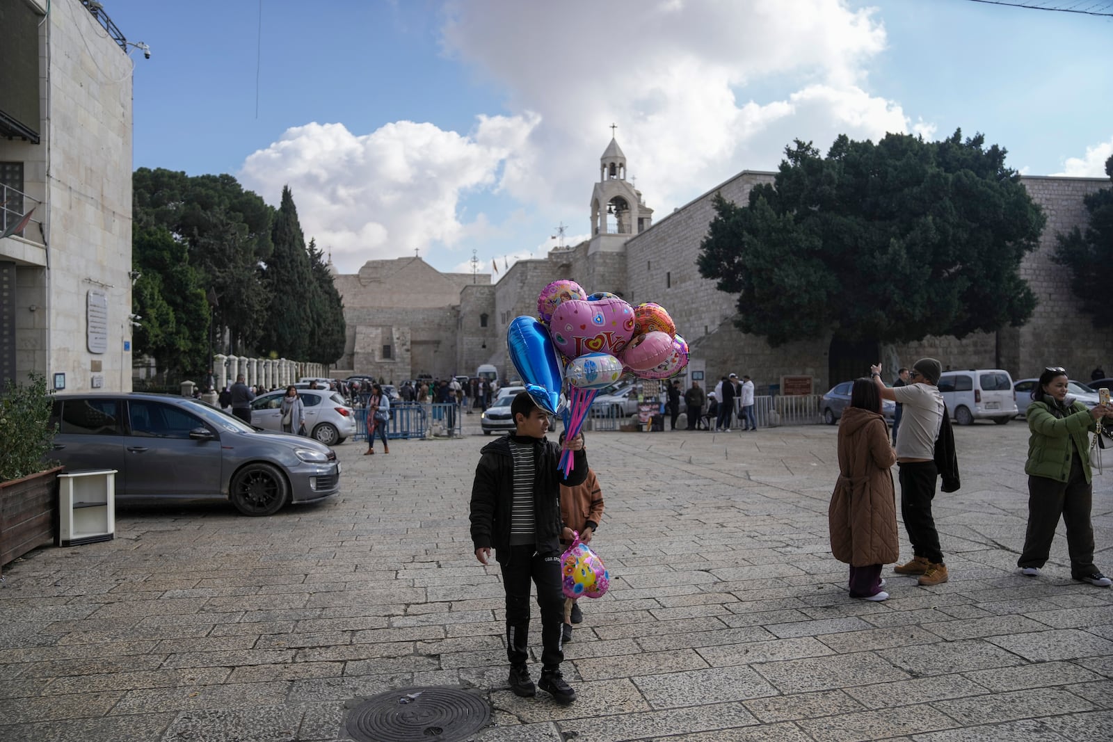 A boy sells balloons outside the Church of the Nativity, where Christians believe Jesus Christ was born, ahead of Christmas in the West Bank city of Bethlehem, Saturday Dec. 21, 2024. (AP Photo/Mahmoud Illean)