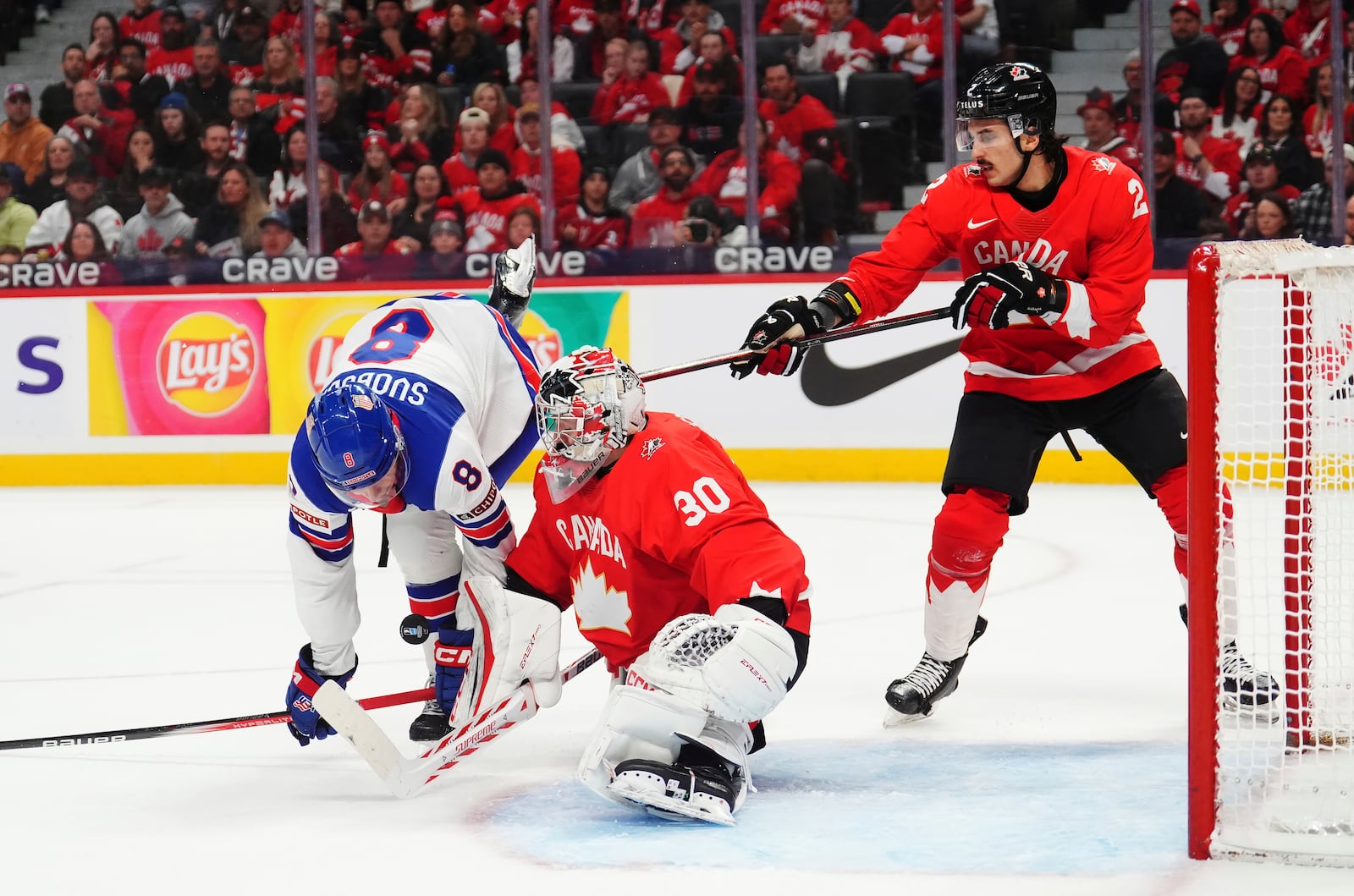 Canada goaltender Carter George (30) makes a save as United States' Brandon Svoboda (8) stumbles and Canada's Andrew Gibson (2) defends during the first period of an IIHF World Junior Hockey Championship tournament game in Ottawa, Ontario on Tuesday, Dec. 31, 2024. (Sean Kilpatrick/The Canadian Press via AP)