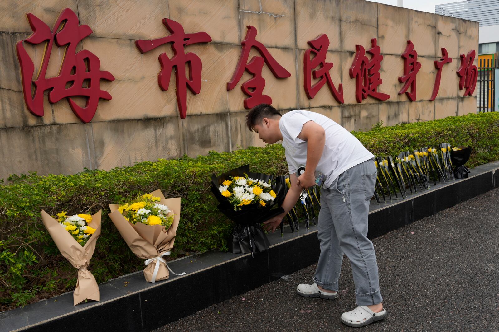 A man lays flowers outside the "Zhuhai People's Fitness Plaza" where a man rammed his car into people exercising at the sports center, in Zhuhai in southern China's Guangdong province on Wednesday, Nov. 13, 2024. (AP Photo/Ng Han Guan)