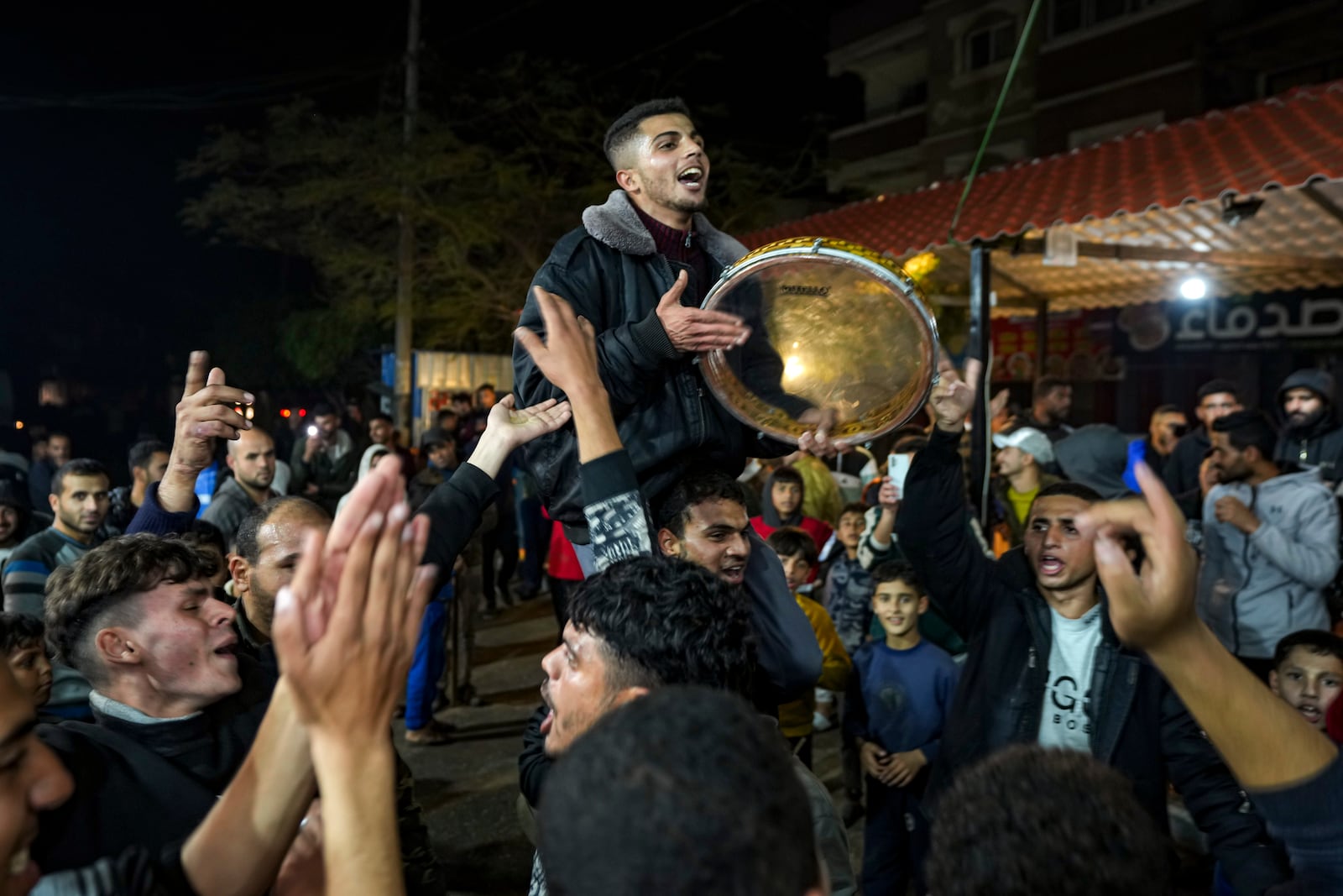 Palestinians celebrate the announcement of a ceasefire deal between Hamas and Israel in Deir al-Balah, central Gaza Strip, Wednesday, Jan. 15, 2025. (AP Photo/Abdel Kareem Hana)