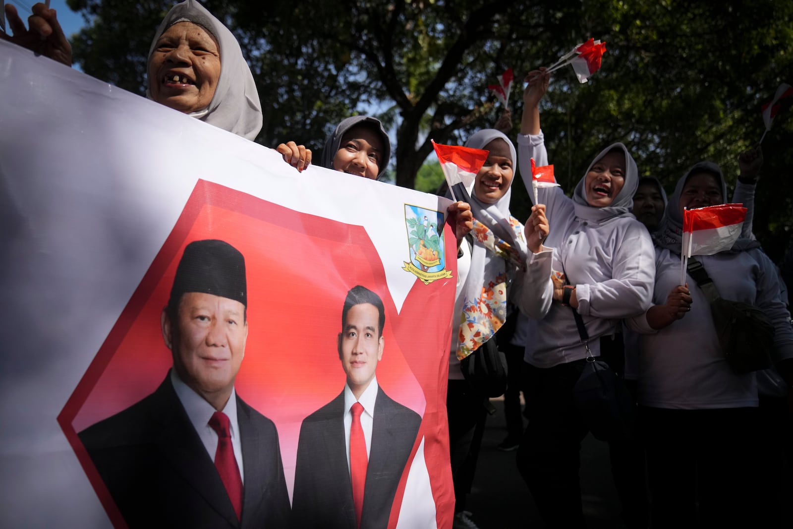 Indonesian supporters waves Indonesia flag and hold banner show Indonesian president-elect Prabowo Subianto, left, and vice president-elect Gibran Rakabuming Raka, who is also the eldest son of outgoing President Joko Widodo in Jakarta, Indonesia, Sunday, Oct. 20, 2024. (AP Photo/Dita Alangkara)