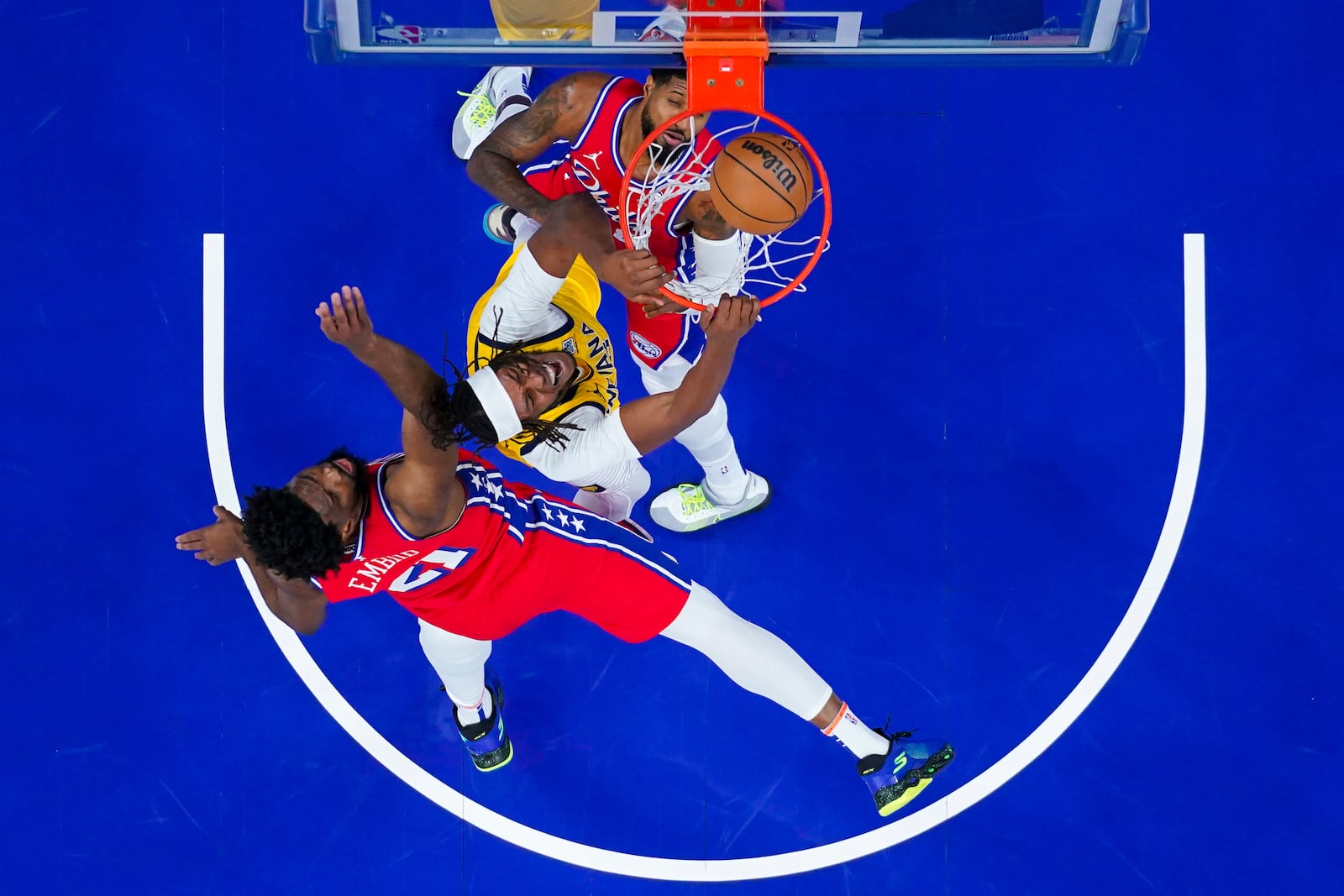 Indiana Pacers' Myles Turner, center, dunks the ball as Philadelphia 76ers' Joel Embiid, left, and Paul George, right, are defend during the first half of an NBA basketball game, Friday, Dec. 13, 2024, in Philadelphia. (AP Photo/Chris Szagola)