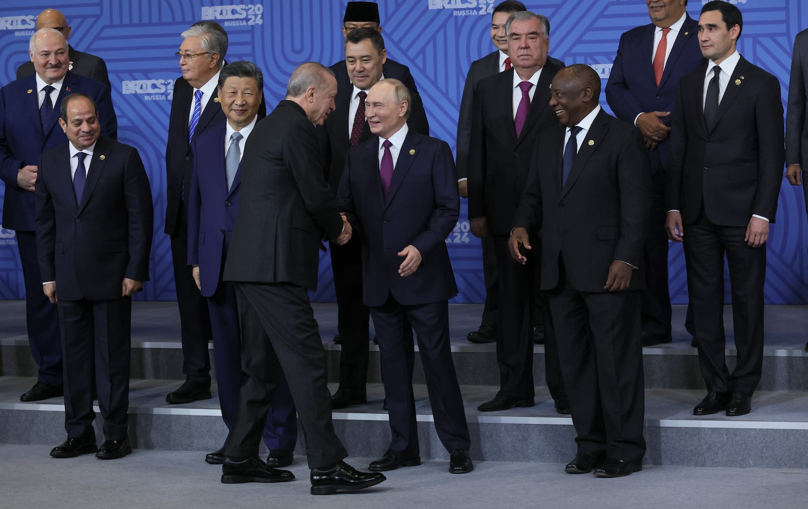 Russian President Vladimir Putin, center, shakes hands with Turkish President Recep Tayyip Erdogan during posing for a family photo prior to Outreach/BRICS Plus format session at the BRICS Summit in Kazan, Russia, Thursday, Oct. 24, 2024. (Maxim Shipenkov, Pool Photo via AP)