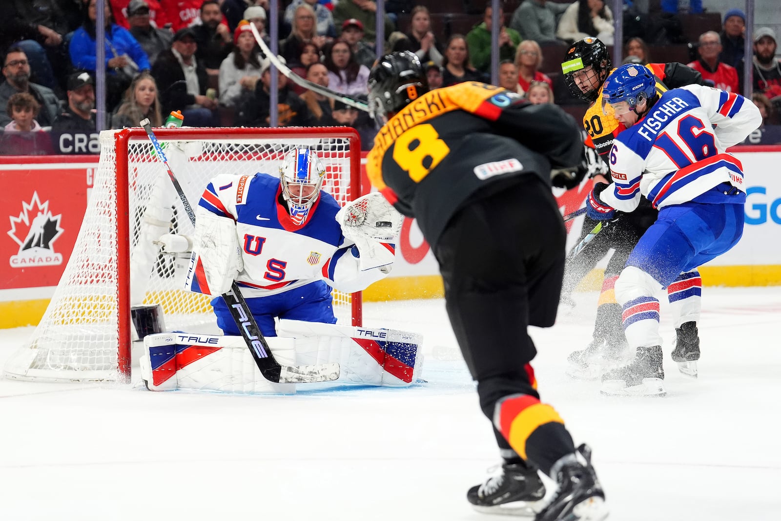 United Sttaes goaltender Trey Augustine (1) makes a glove-save against Germany forward Noah Samanski (8) during second-period IIHF World Junior Hockey Championship preliminary round game action in Ottawa, Ontario, Thursday, Dec. 26, 2024. (Sean Kilpatrick/The Canadian Press via AP)