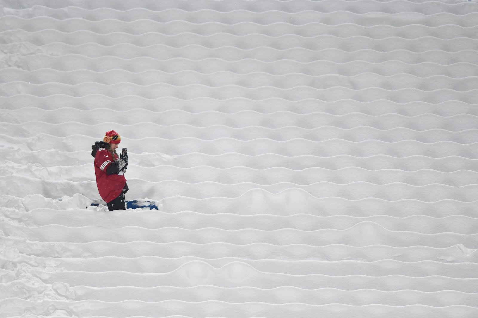 A San Francisco 49ers fan stands between snow covered seats before an NFL football game between the Buffalo Bills and the 49ers in Orchard Park, N.Y., Sunday, Dec. 1, 2024. (AP Photo/Adrian Kraus)