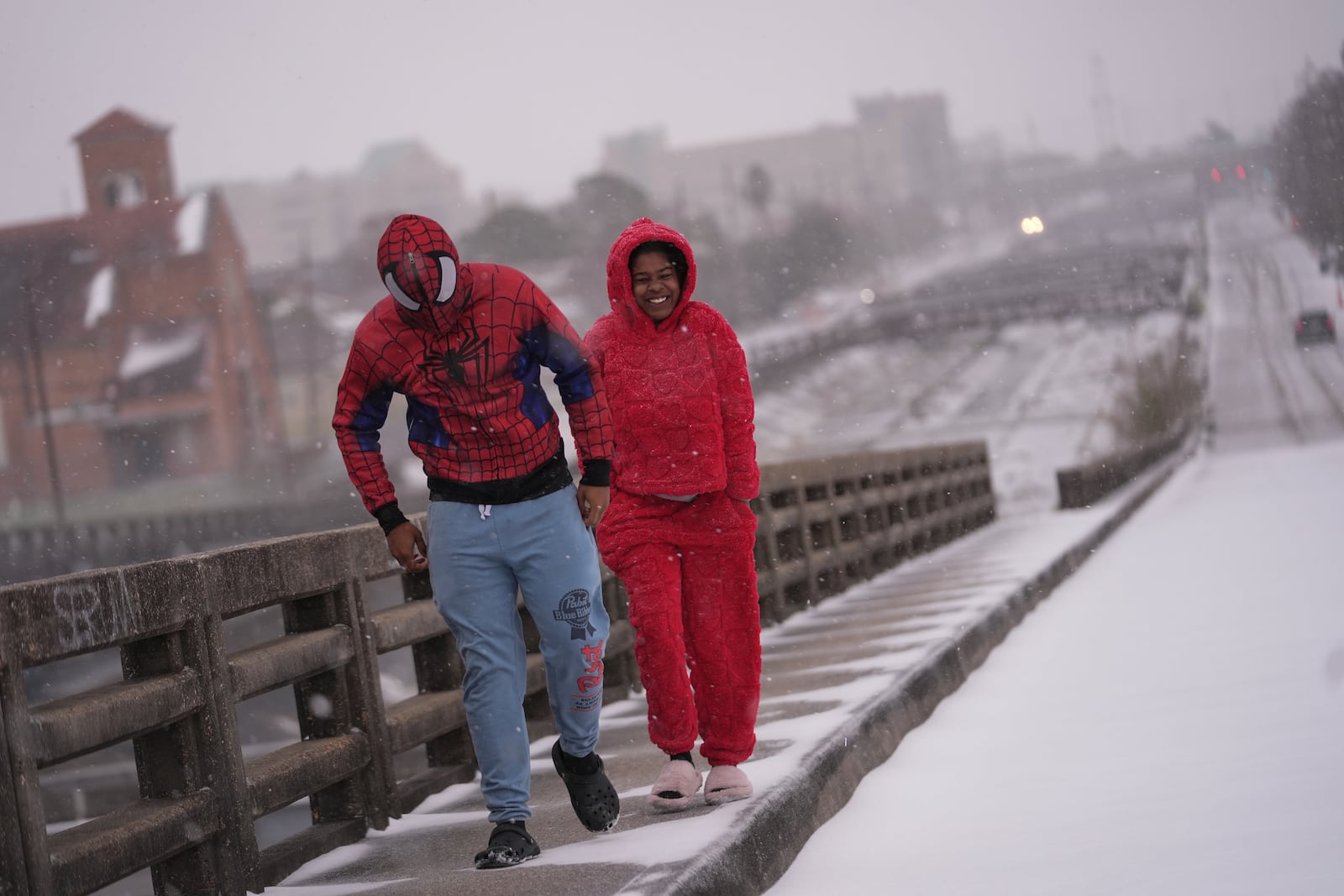 Abel Allen, in a Spider-Man suit, and Angel Tircuit walk on a snow covered bridge in New Orleans, Tuesday, Jan. 21, 2025. (AP Photo/Gerald Herbert)