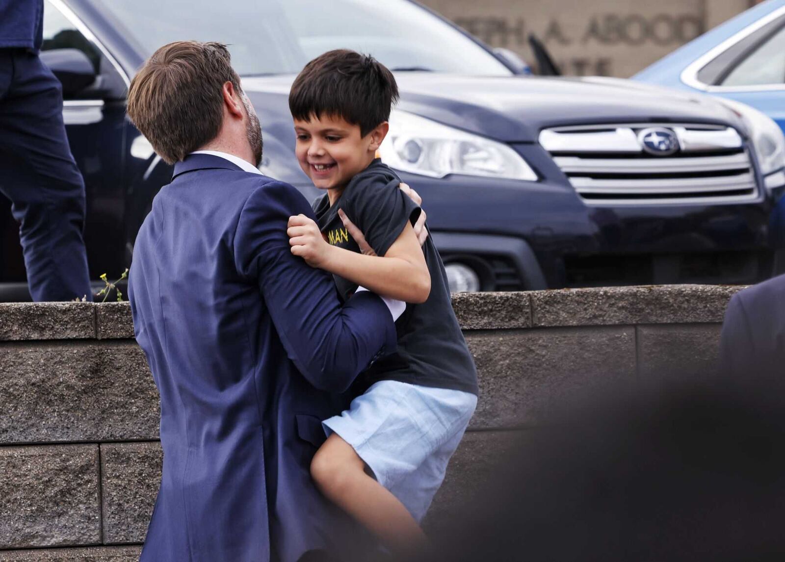 JD Vance catches one of his sons who wanted to jump off a wall Tuesday morning after Vance and his wife voted in Cincinnati. NICK GRAHAM/STAFF