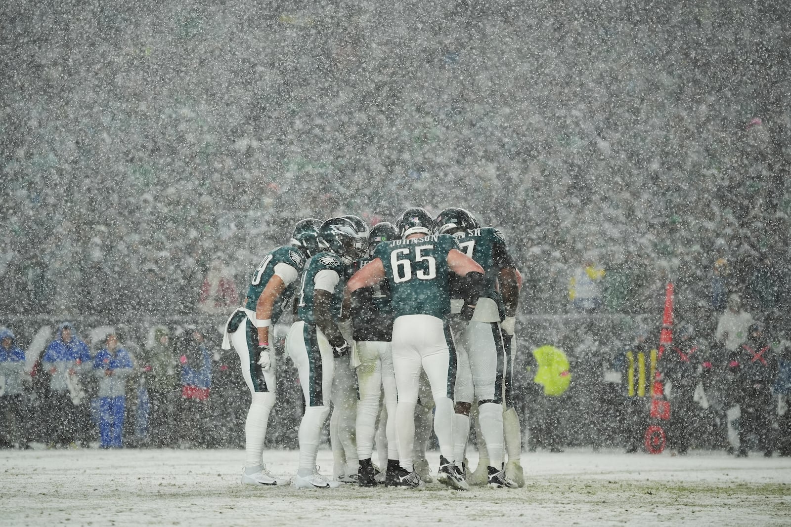 Philadelphia Eagles players huddle as it snows during the second half of an NFL football NFC divisional playoff game against the Los Angeles Rams on Sunday, Jan. 19, 2025, in Philadelphia. (AP Photo/Matt Slocum)