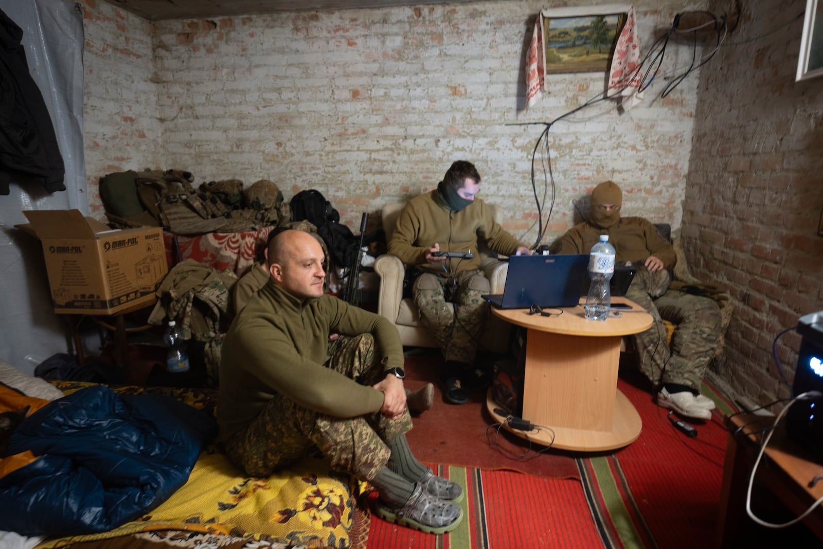 Ukraine's Khartia brigade officer, who goes by callsign Kit, left, sits while his soldiers pilot drones in a shelter on the frontline near Kharkiv, Ukraine, late Thursday, Nov. 7, 2024. (AP Photo/Efrem Lukatsky)