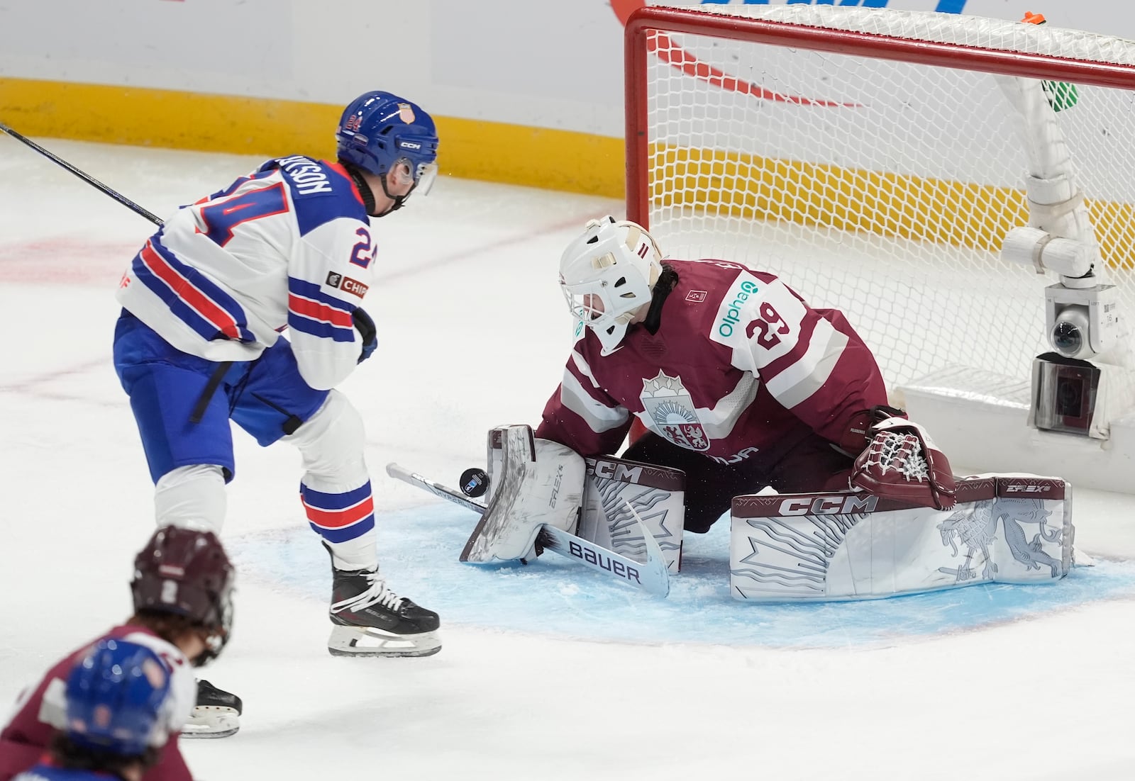 United States defenseman Cole Hutson (24) pressures Latvia goaltender Linards Feldbergs (29) as he makes a save during the first period of a IIHF World Junior Hockey Championship tournament game, Saturday, Dec.28, 2024 in Ottawa, Ontario. (Adrian Wyld/The Canadian Press via AP)