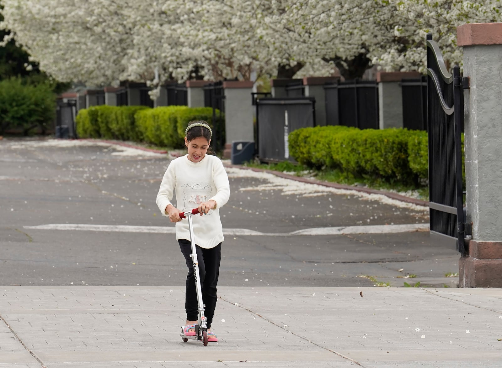 Nargis Osmani rides a scooter near the new home provided to the Afghan family by the No One Left Behind Organization, in Rancho Cordova, Calif., Wednesday, March 12, 2025. (AP Photo/Rich Pedroncelli)