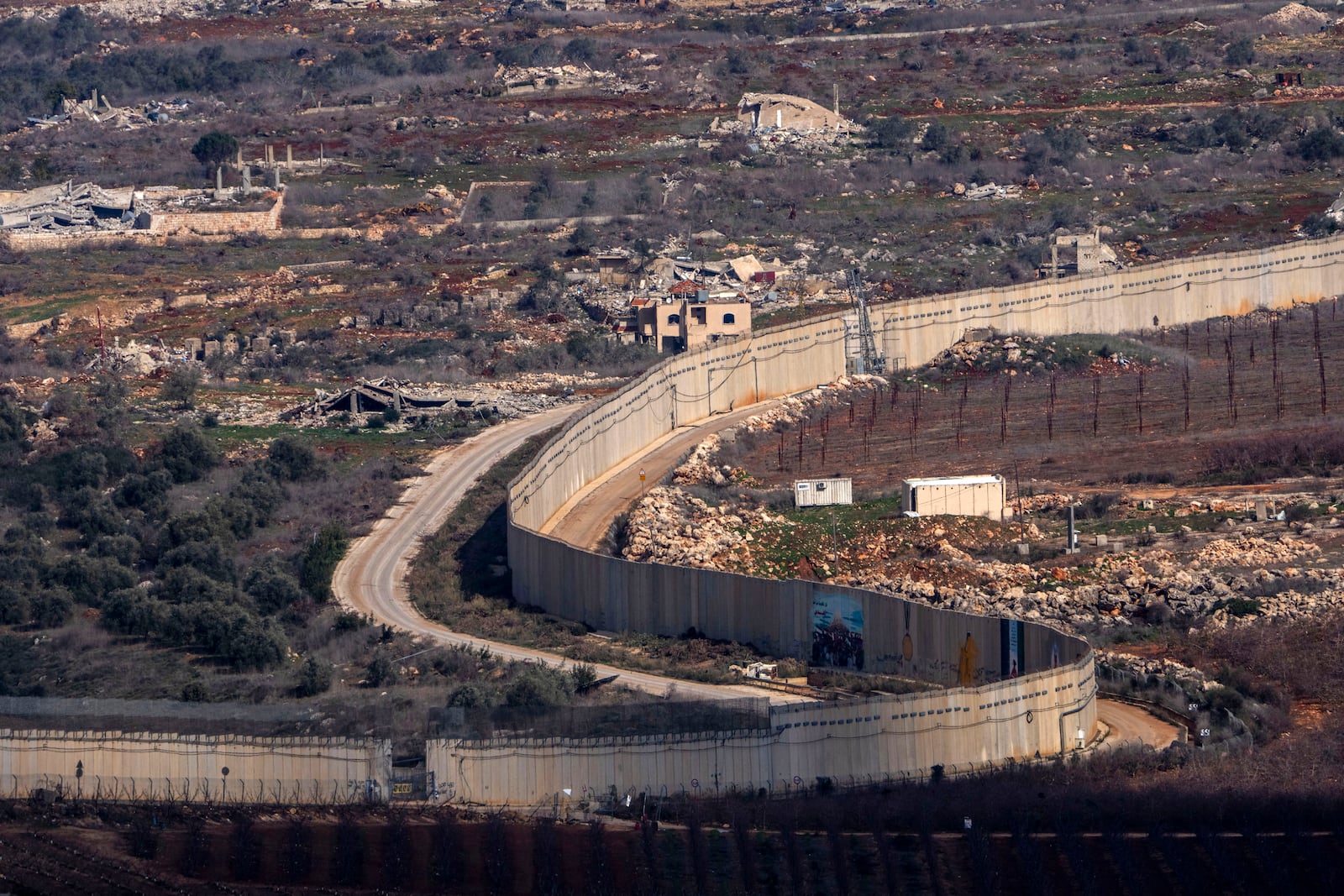 A wall marks the Israeli-Lebanese border near the village of Odaisseh in southern Lebanon, as seen from northern Israel, Thursday, Jan. 23, 2025. (AP Photo/Ariel Schalit)