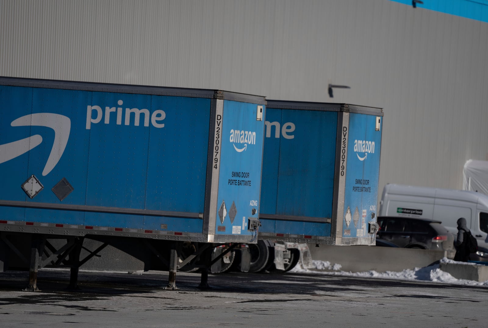 An employee walks past trucks at Amazon's DXT4 warehouse in Laval, Que., Wednesday, Jan. 22, 2025. Amazon Canada says it is closing all seven of its warehouses in Quebec. (Christinne Muschi /The Canadian Press via AP)