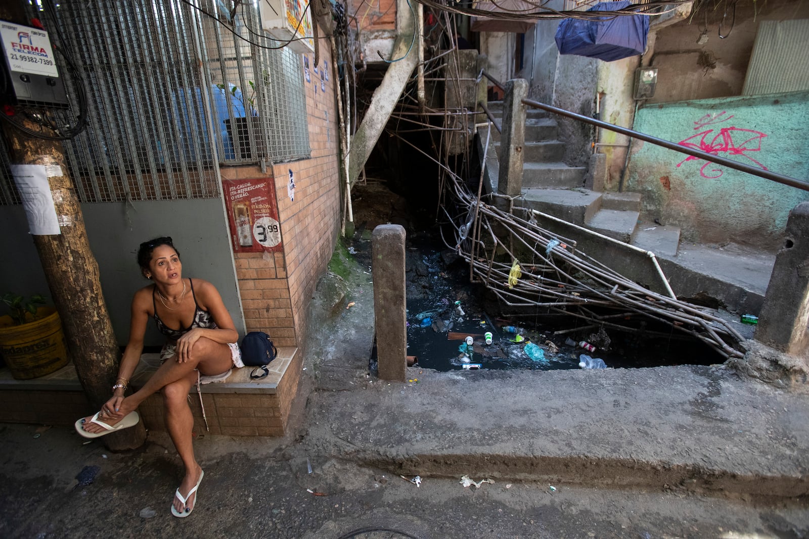 Carla do Nascimento Gomes sits in an alley where sewage water passes through the Rocinha favela in Rio de Janeiro, Wednesday, Nov. 6, 2024. (AP Photo/Bruna Prado)