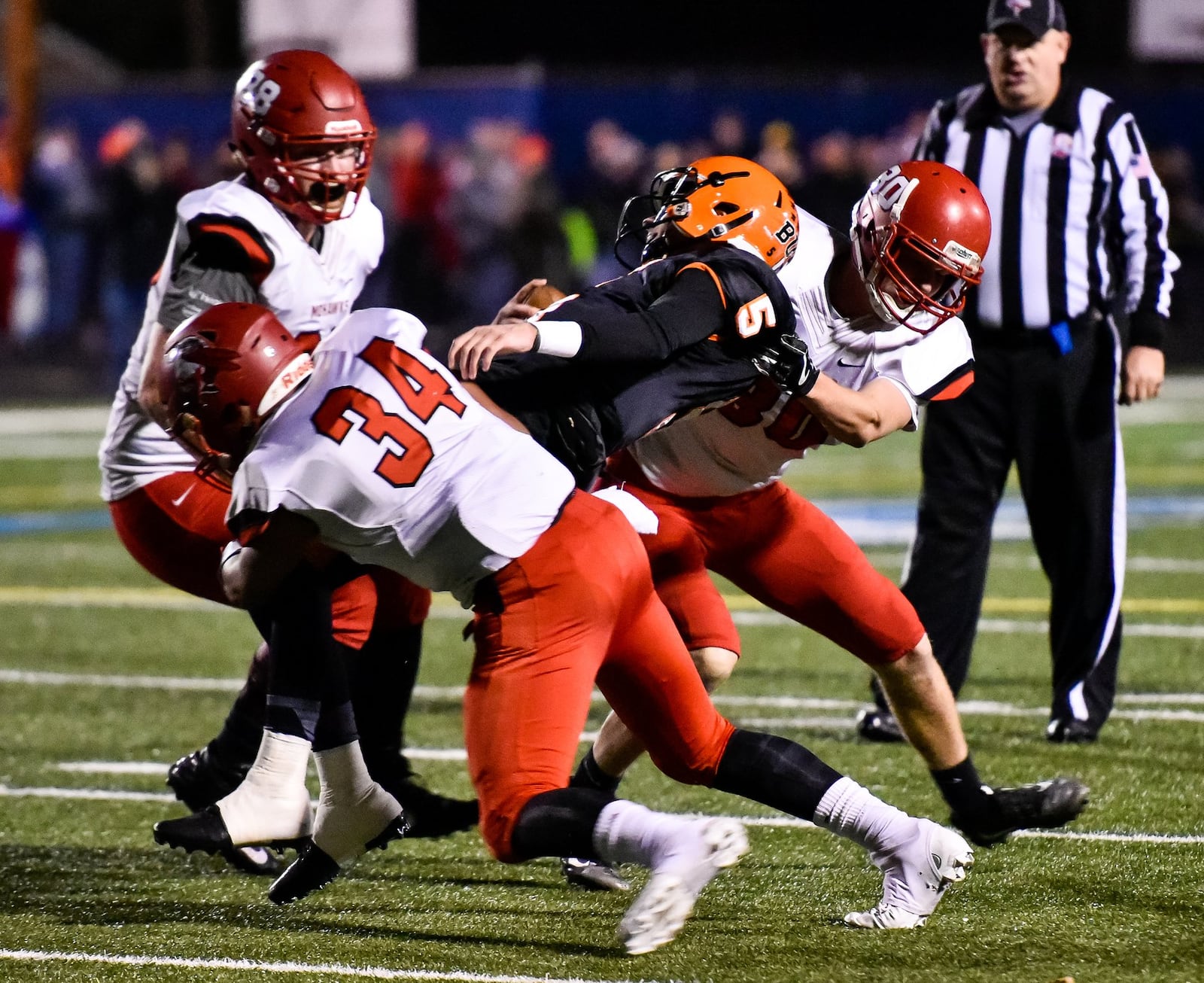 Madison’s Evan Crim (34), Levi McMonigle (30) and Max Evans (38) take down Wheelersburg quarterback Trent Salyers during a Division V state semifinal Nov. 24, 2017, at Herrnstein Field in Chillicothe. NICK GRAHAM/STAFF