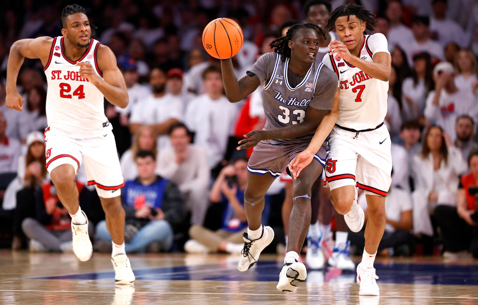 Seton Hall guard Garwey Dual (33) drives upcourt against St. John's forward Zuby Ejiofor (24) and guard Simeon Wilcher (7) during the first half of an NCAA college basketball game, Saturday, March 1, 2025, in New York. (AP Photo/Noah K. Murray)