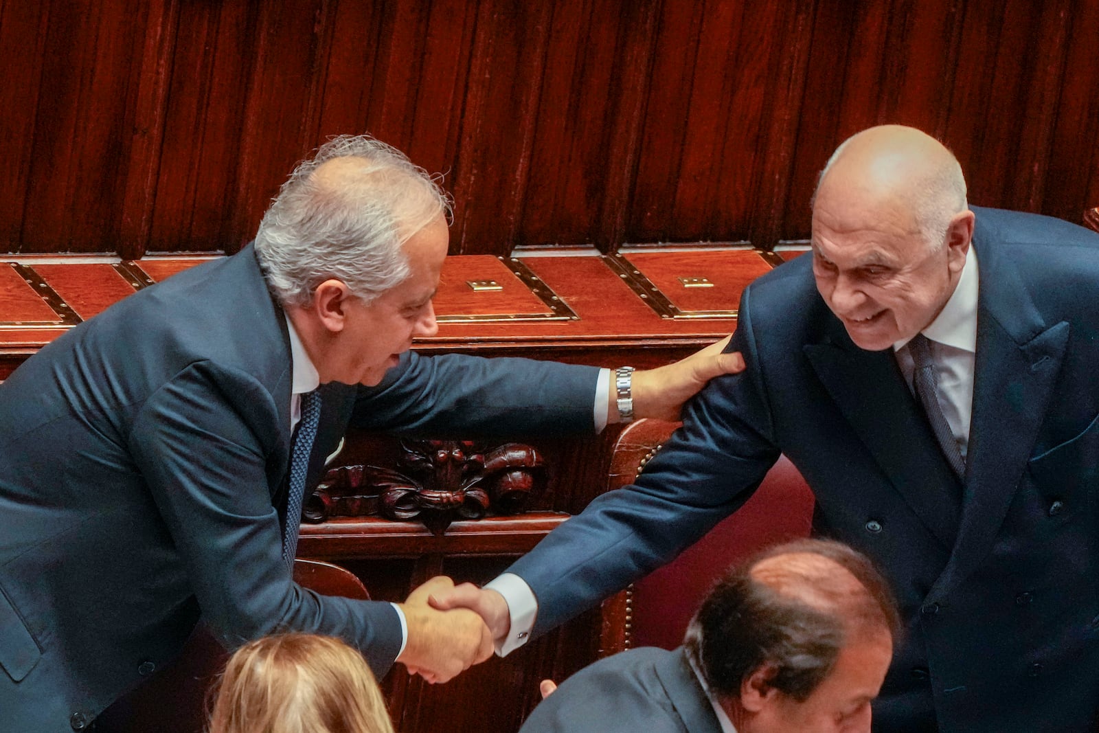 Italian Justice Minister Carlo Nordio, right, is congratulated by Interior Minister Matteo Piantedosi after speaking during a debate in the Italian lower Chamber in Rome, Wednesday, Feb. 5, 2025, over the controversial repatriation, last week, of a Libyan warlord, Ossama Anjiem, also known as Ossama al-Masri, wanted by the International Criminal Court in the Hague, and who had been arrested in Turin, northern Italy. (AP Photo/Gregorio Borgia)