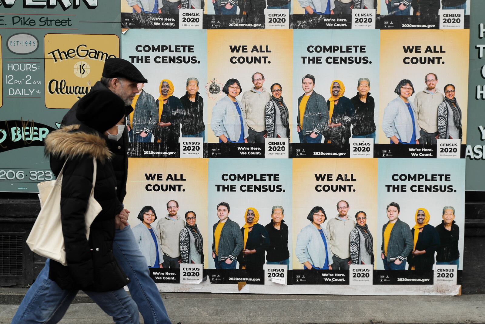 FILE - People walk past posters encouraging participation in the 2020 Census in Seattle's Capitol Hill neighborhood, April 1, 2020.(AP Photo/Ted S. Warren, File)