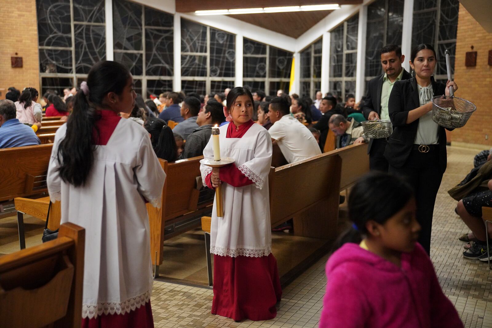 Altar servers stand at the back of the sanctuary as ushers collect offerings during the Spanish-language Mass at St. Mary’s Catholic Church on Saturday, Oct. 19, 2024, in Worthington, Minn. (AP Photo/Jessie Wardarski)