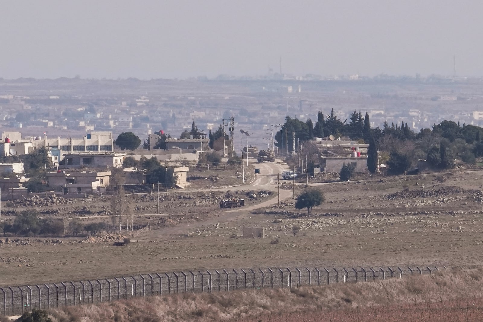 Israeli tanks maneuver in the buffer zone in the Quneitra crossing, between Israel and Syria, are viewed from the Israeli-annexed Golan Heights, Tuesday, Dec. 10, 2024. (AP Photo/Matias Delacroix)