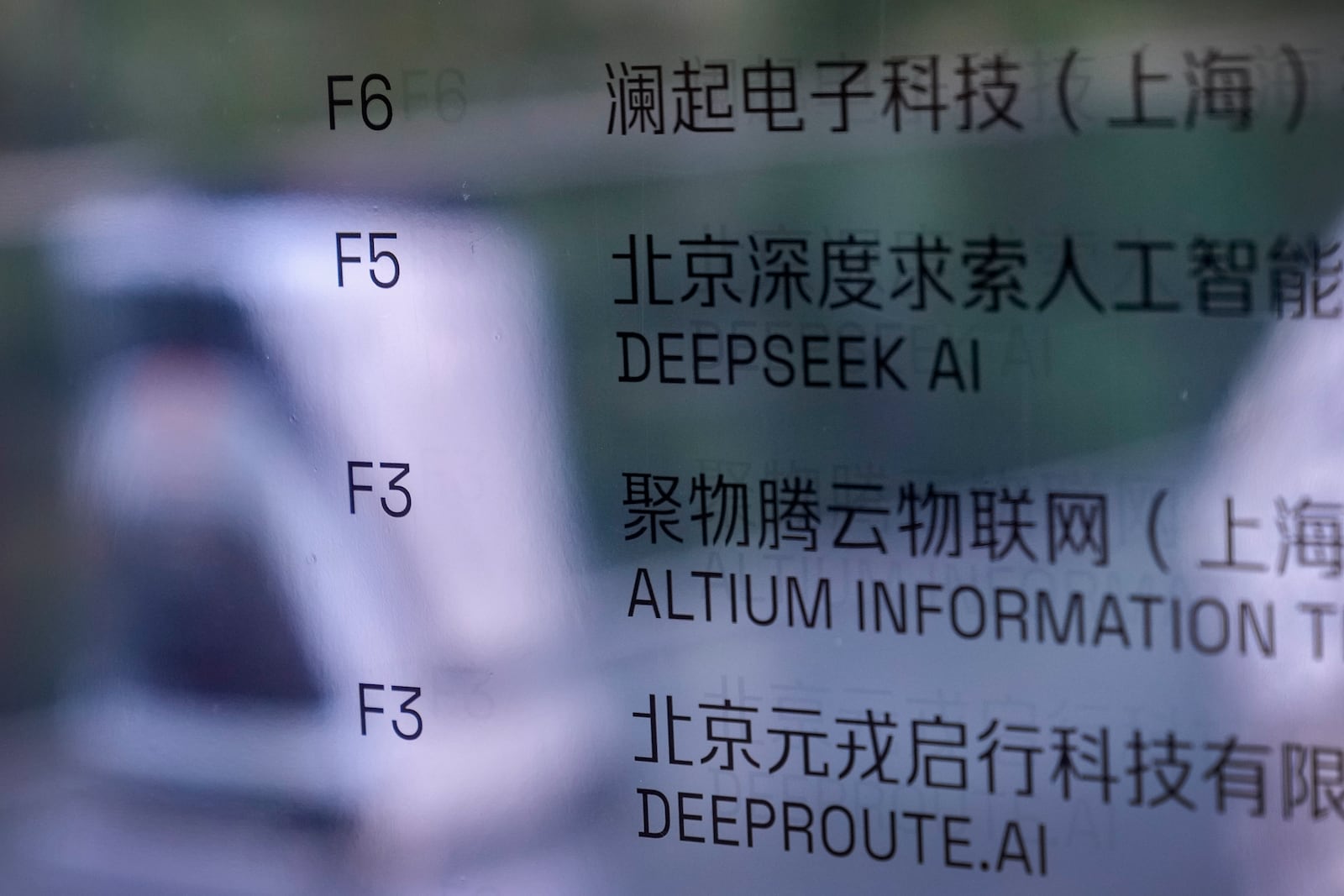 An AI robot moves past an office information board showing the DeepSeek smartphone apps company in Beijing, Tuesday, Jan. 28, 2025. (AP Photo/Andy Wong)