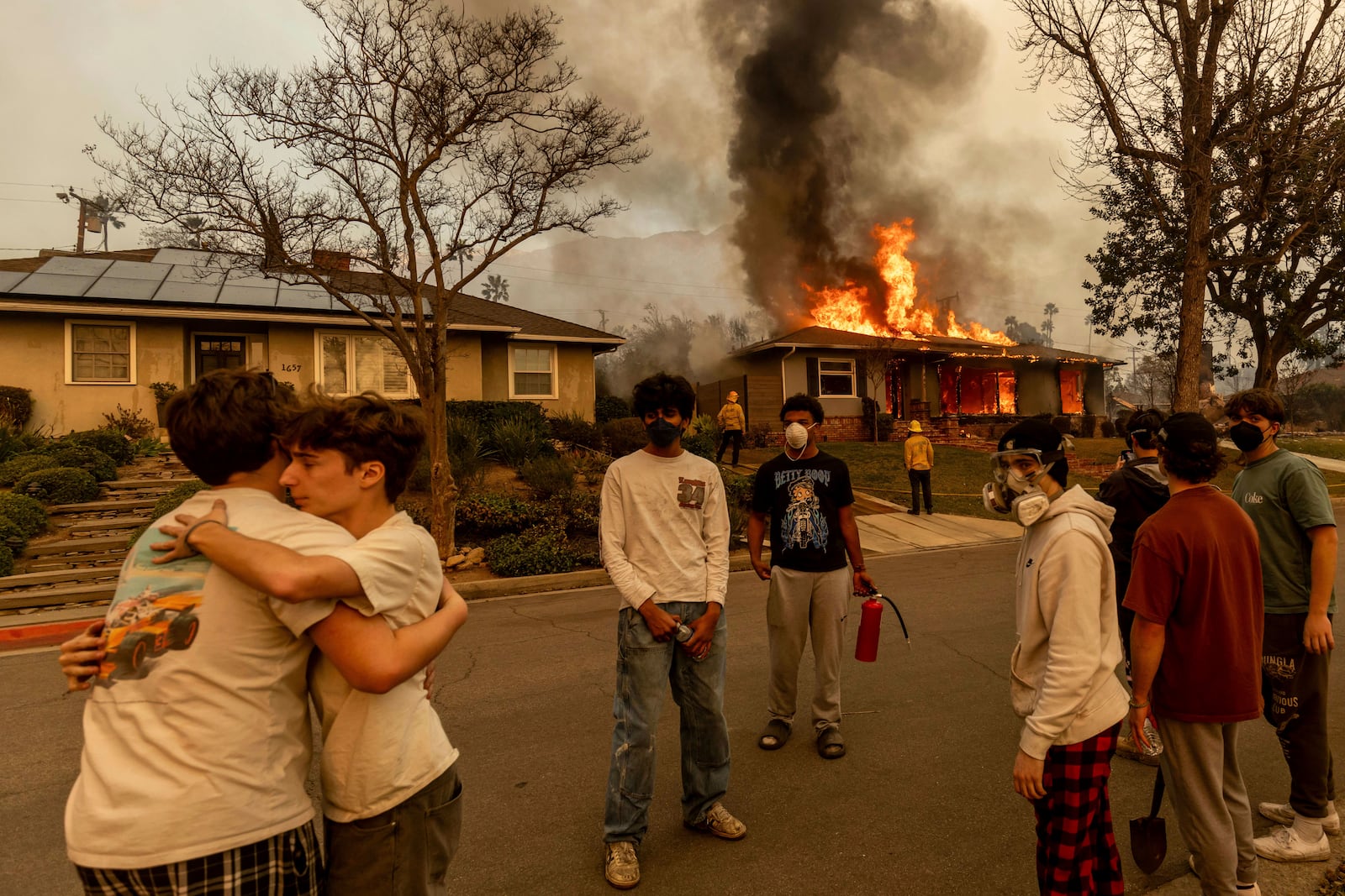 Residents embrace outside of a burning property as the Eaton Fire swept through Wednesday, Jan. 8, 2025 in Altadena, Calif. (AP Photo/Ethan Swope)