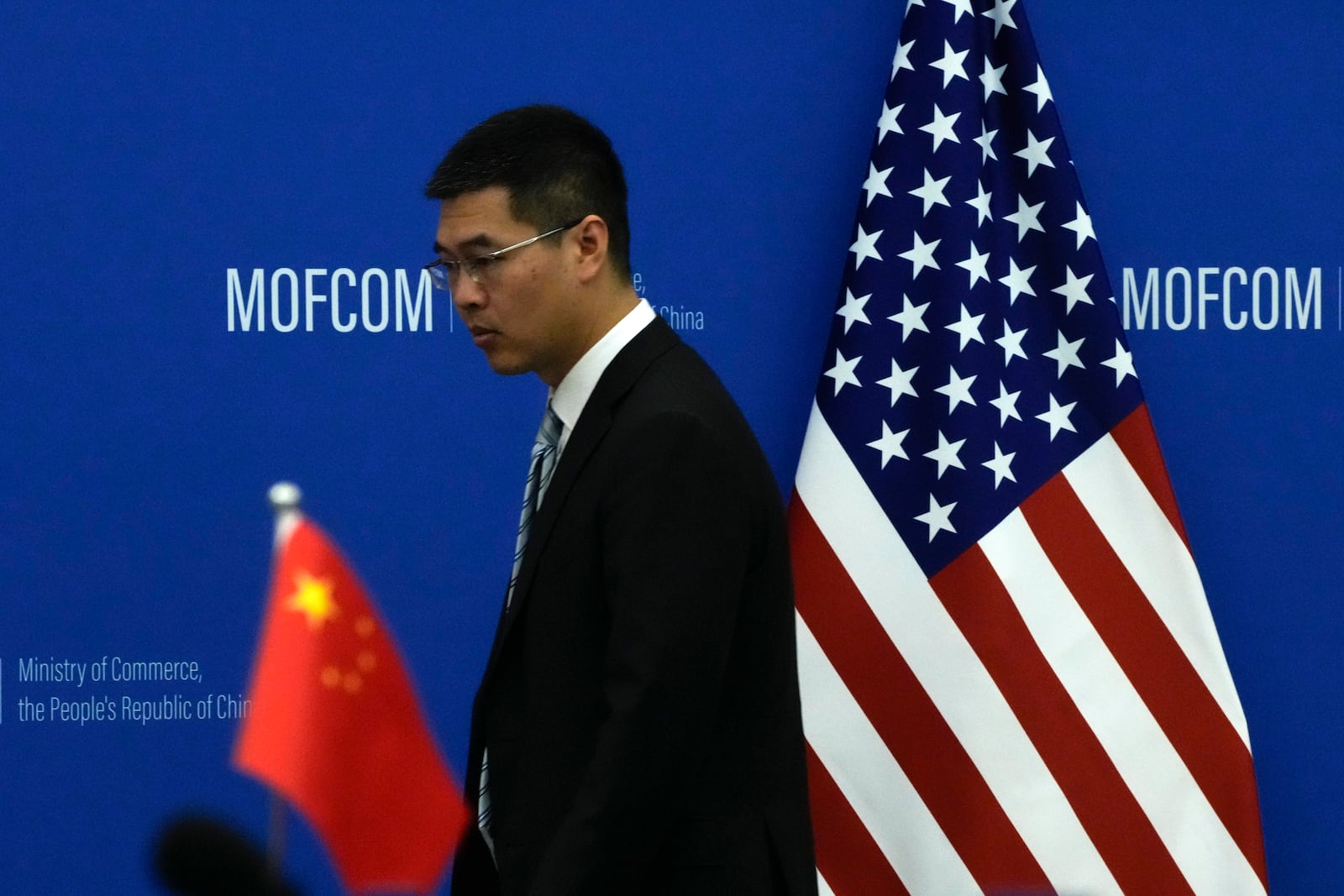 FILE - A Chinese official walks by the China and U.S. national flags before a meeting between Commerce Secretary Gina Raimondo and Chinese Minister of Commerce Wang Wentao at the Ministry of Commerce in Beijing on Aug. 28, 2023. (AP Photo/Andy Wong, Pool, File)